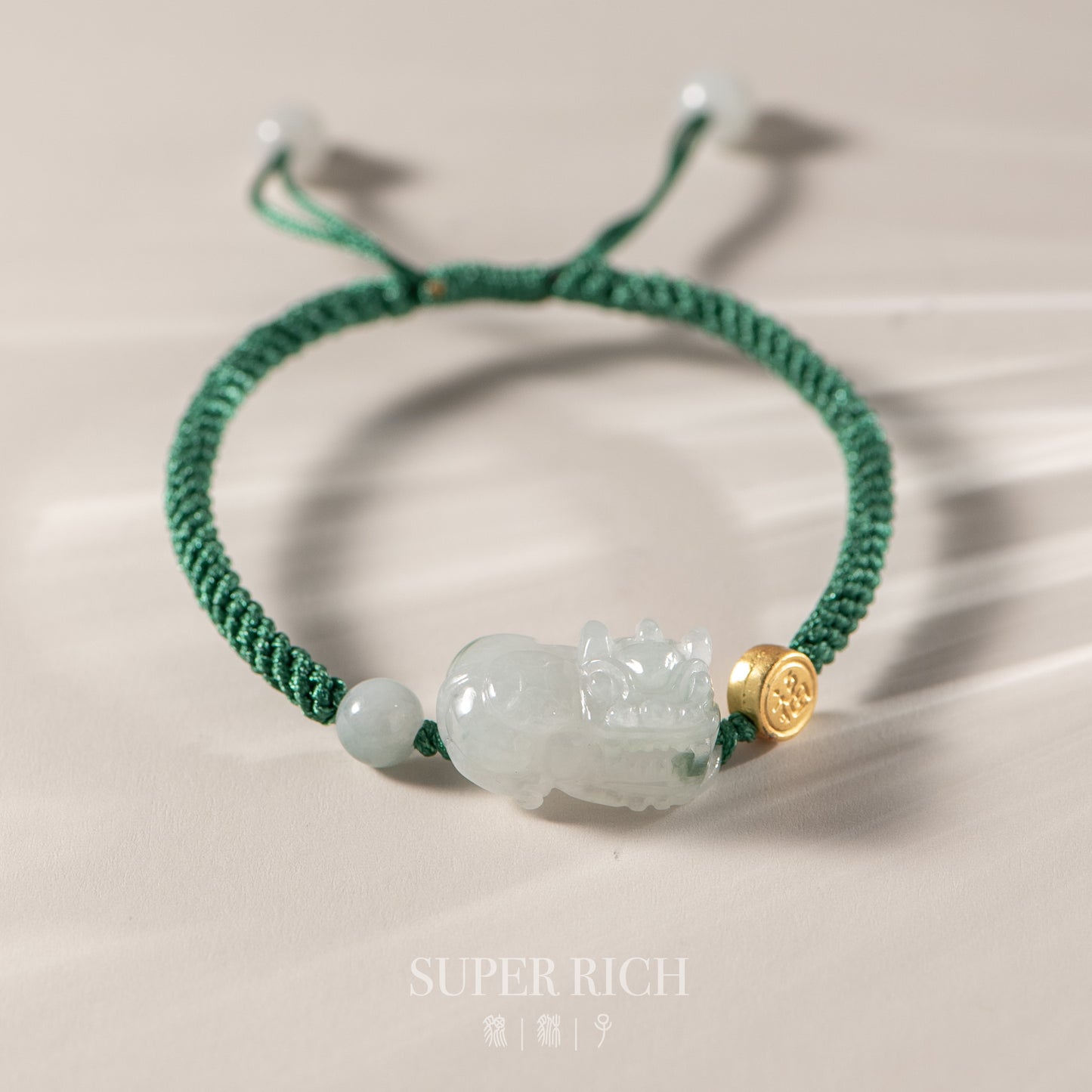Green bracelet with a jade charm and gold accent on a neutral background
