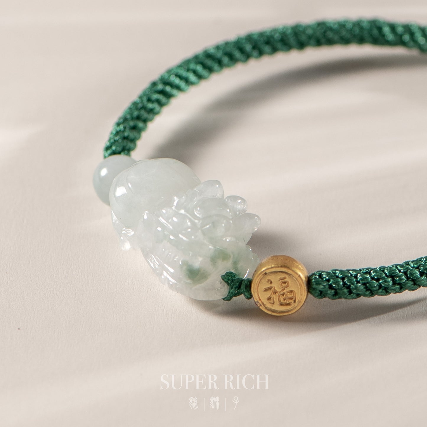 Green bracelet with a jade pendant and gold charm on a light background