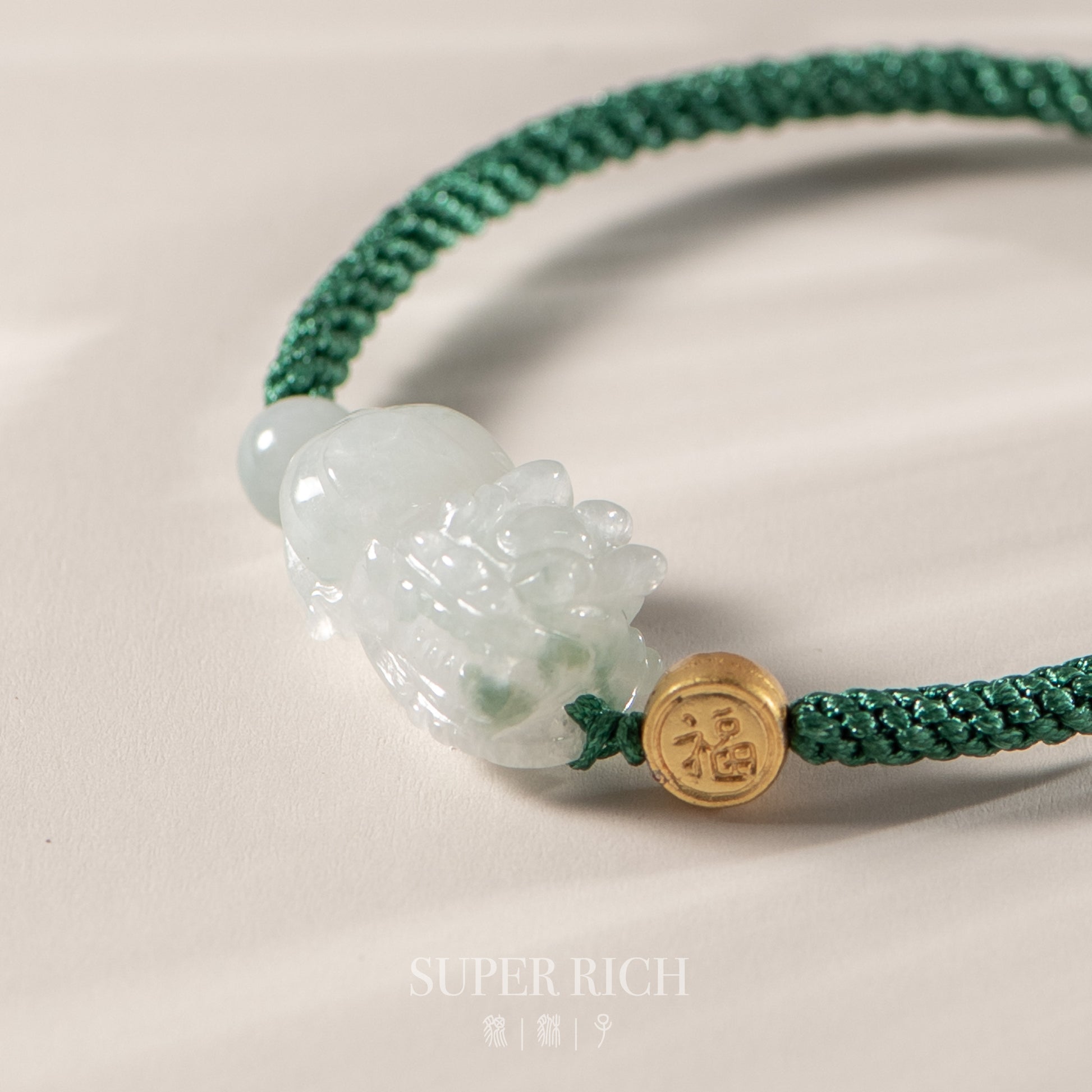 Green bracelet with a jade pendant and gold charm on a light background