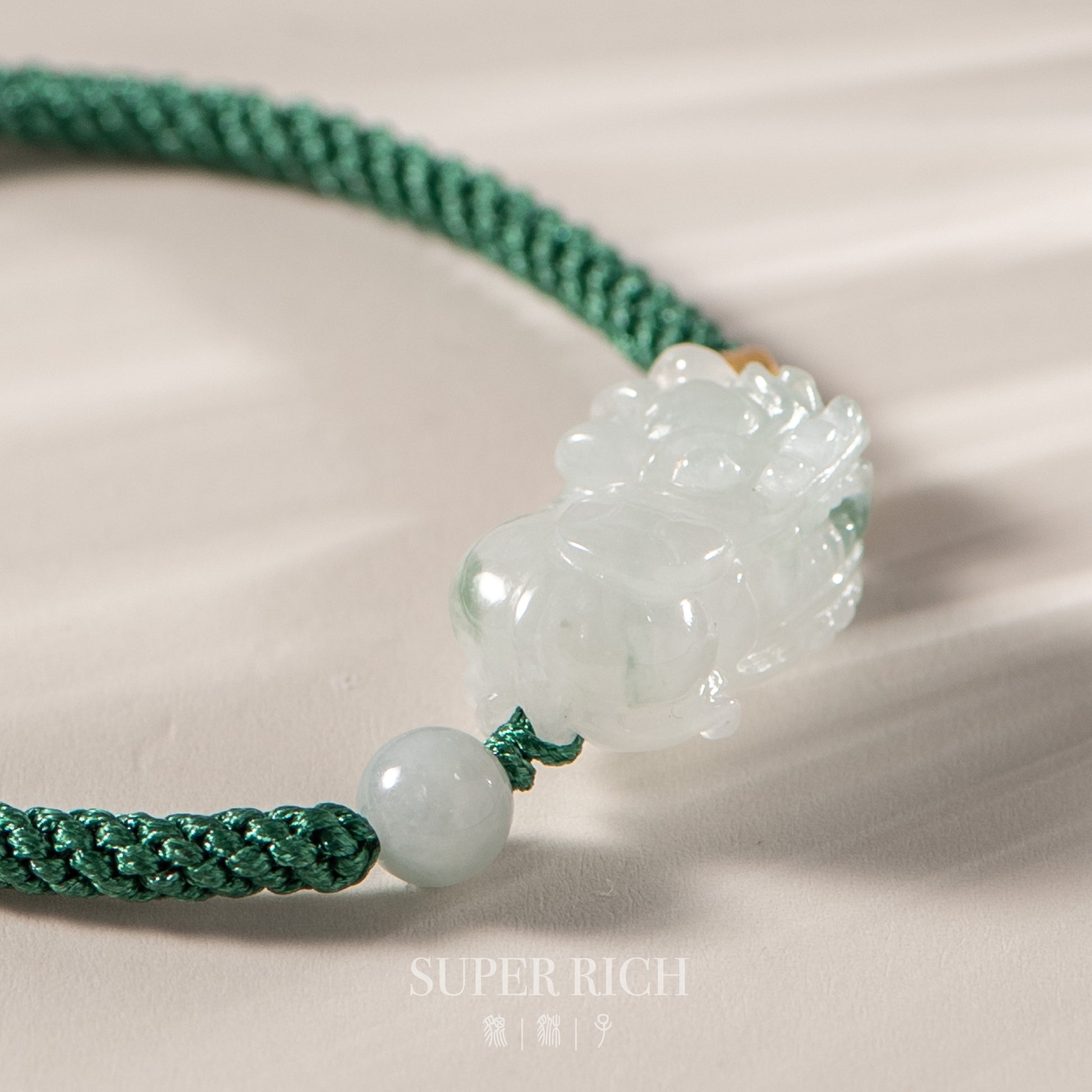Green jade necklace with a carved pendant on a beige background, featuring the brand 'Super Rich'.