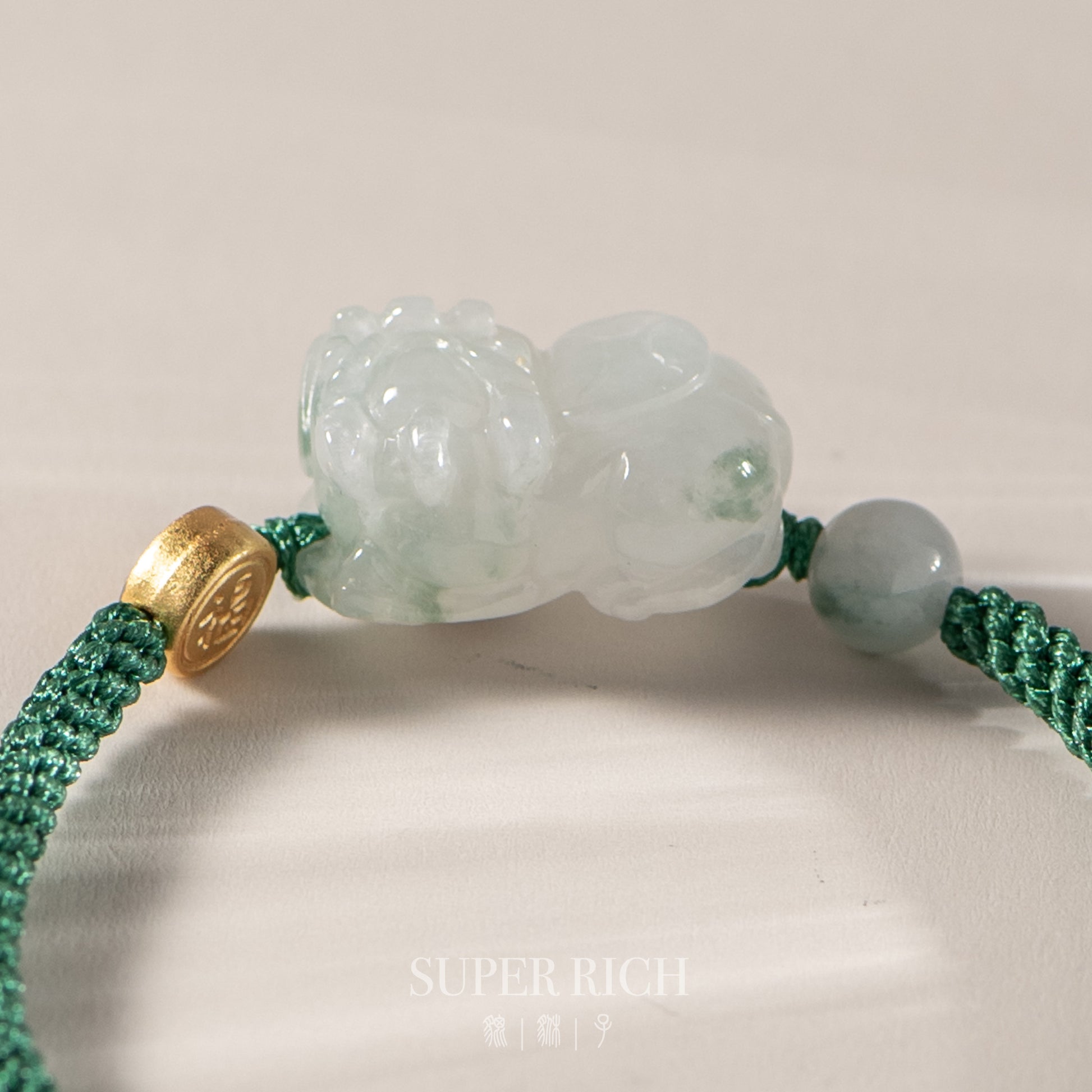 Green jade bracelet with gold clasp on a light background
