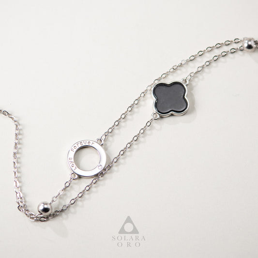 Silver chain necklace with clover-shaped pendant on a white background, featuring Solara Oro logo.