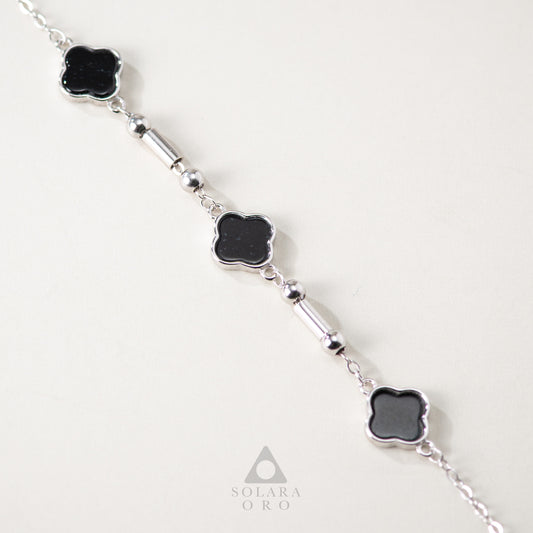 Silver bracelet with black clover-shaped stones on a white background, featuring the brand 'Solara Oro'.