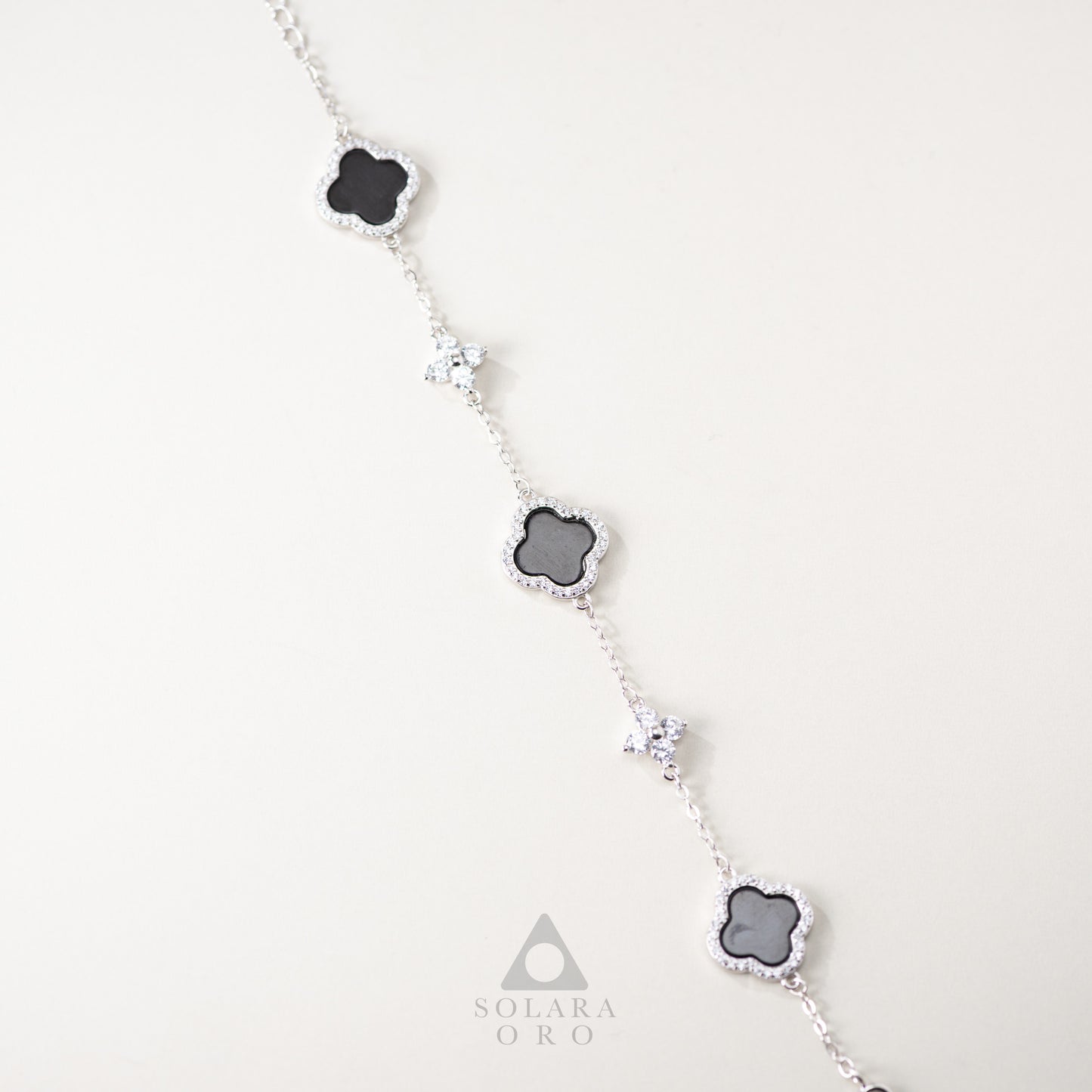 Necklace with clover-shaped pendants on a white background, featuring the Solara Oro brand.