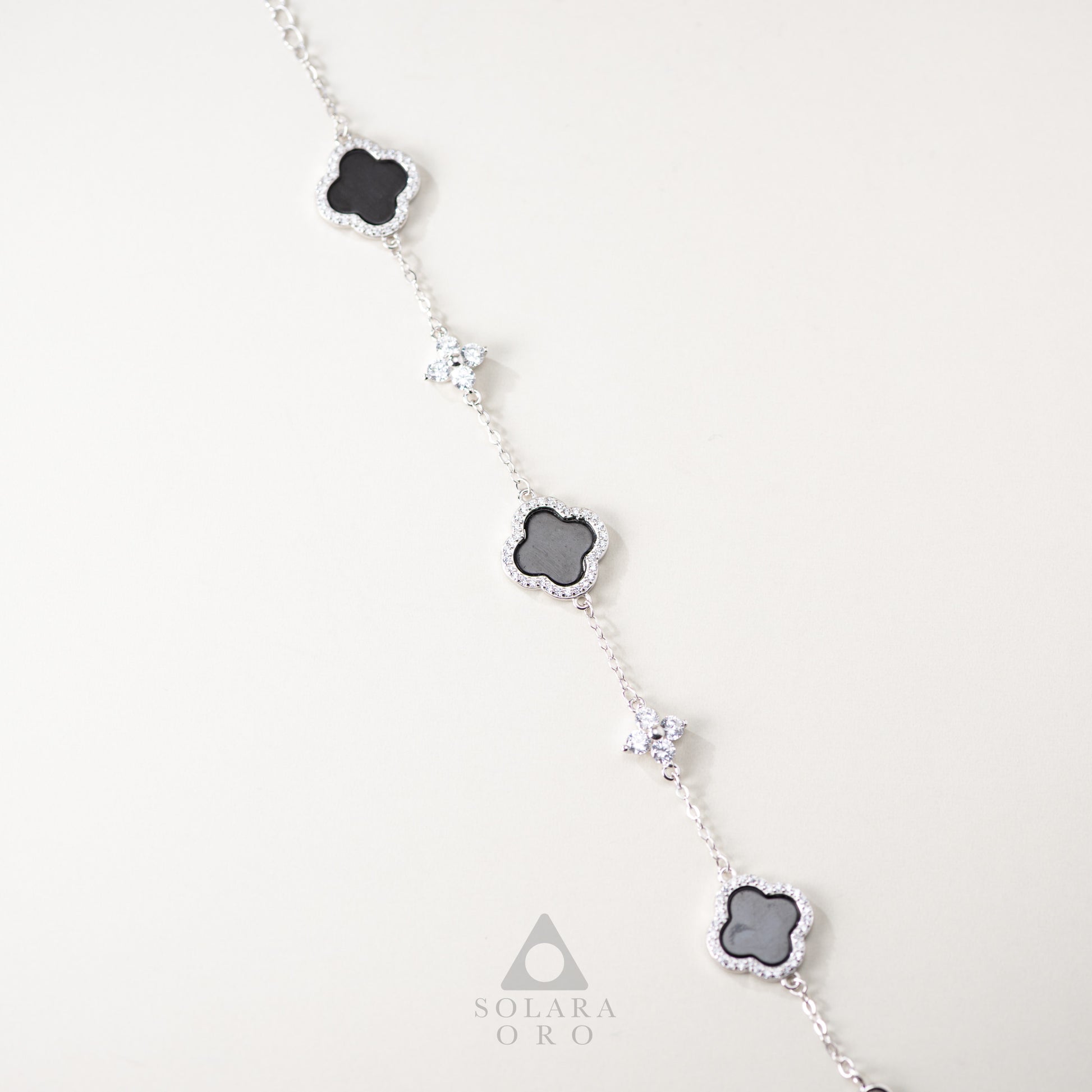 Necklace with clover-shaped pendants on a white background, featuring the Solara Oro brand.