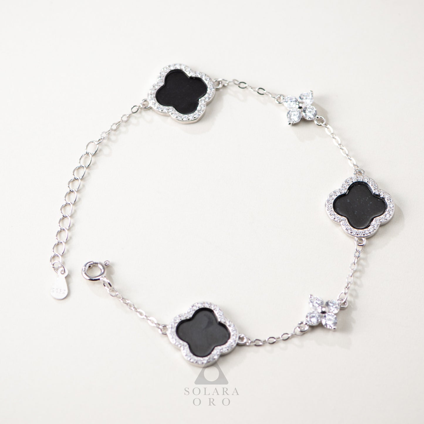 Silver bracelet with black clover-shaped charms on a white background