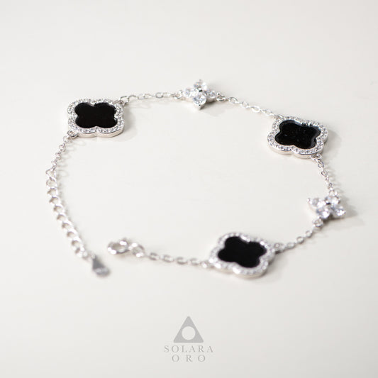 Silver bracelet with black clover-shaped charms on a white background, featuring the Solara Oro brand.