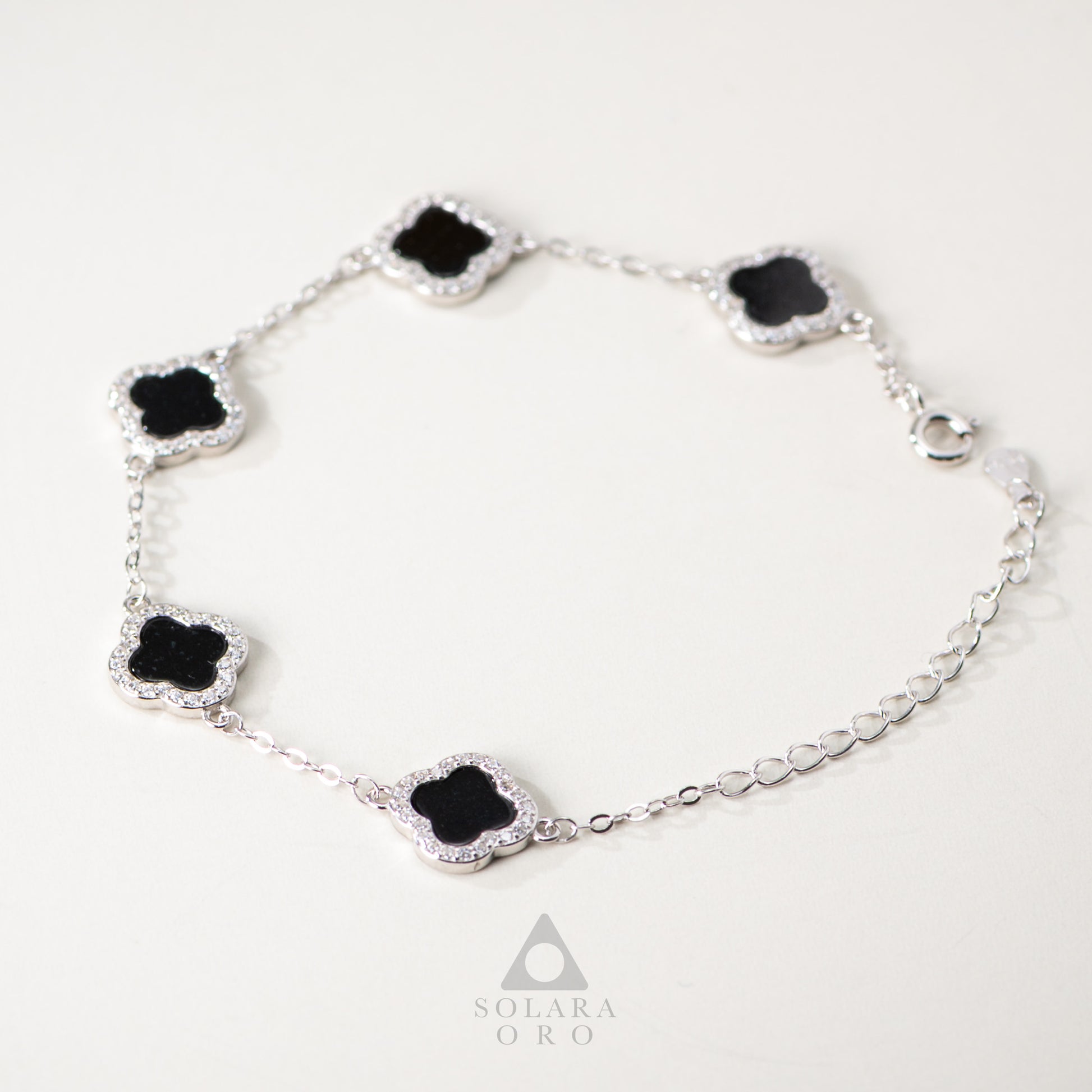 Silver bracelet with black clover-shaped stones on a white background, featuring the brand 'Solara Oro'.