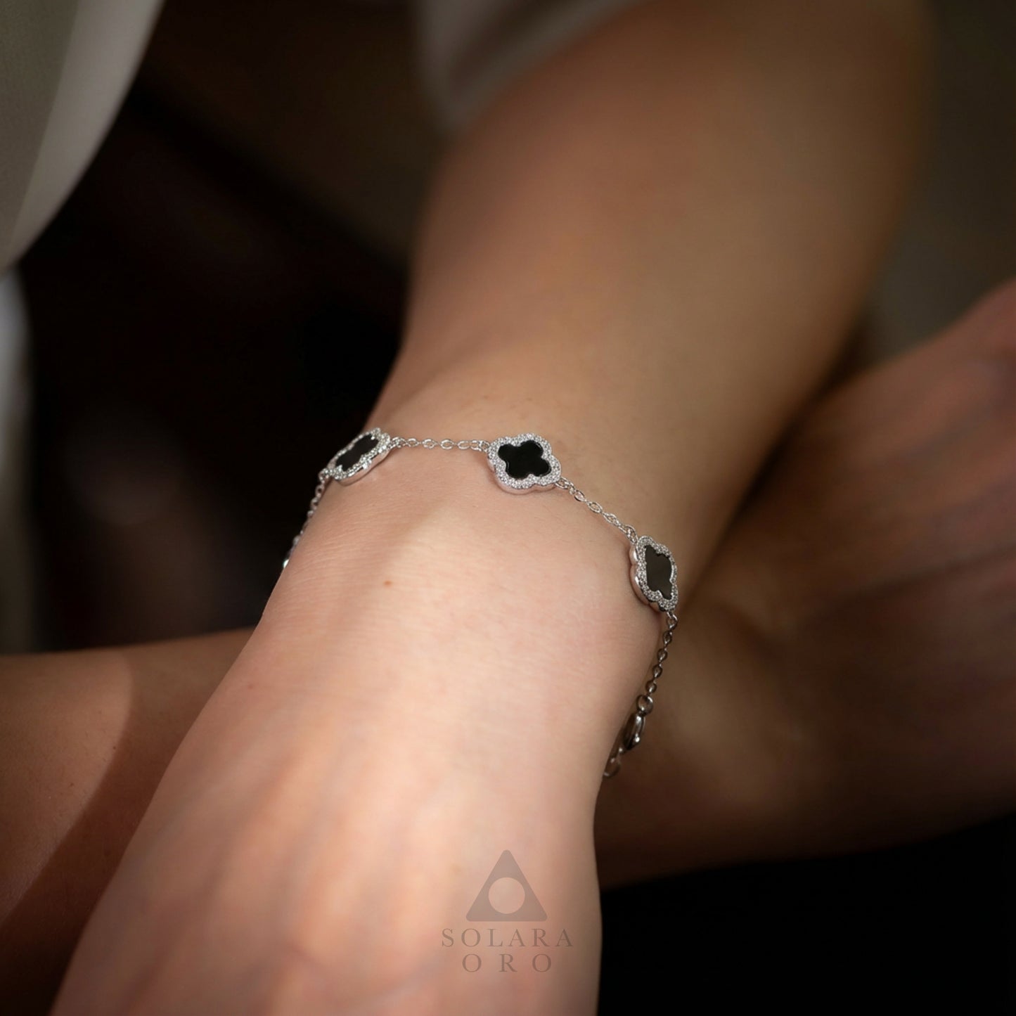 Silver bracelet with black stones on a wrist, brand 'Solara Oro' visible.