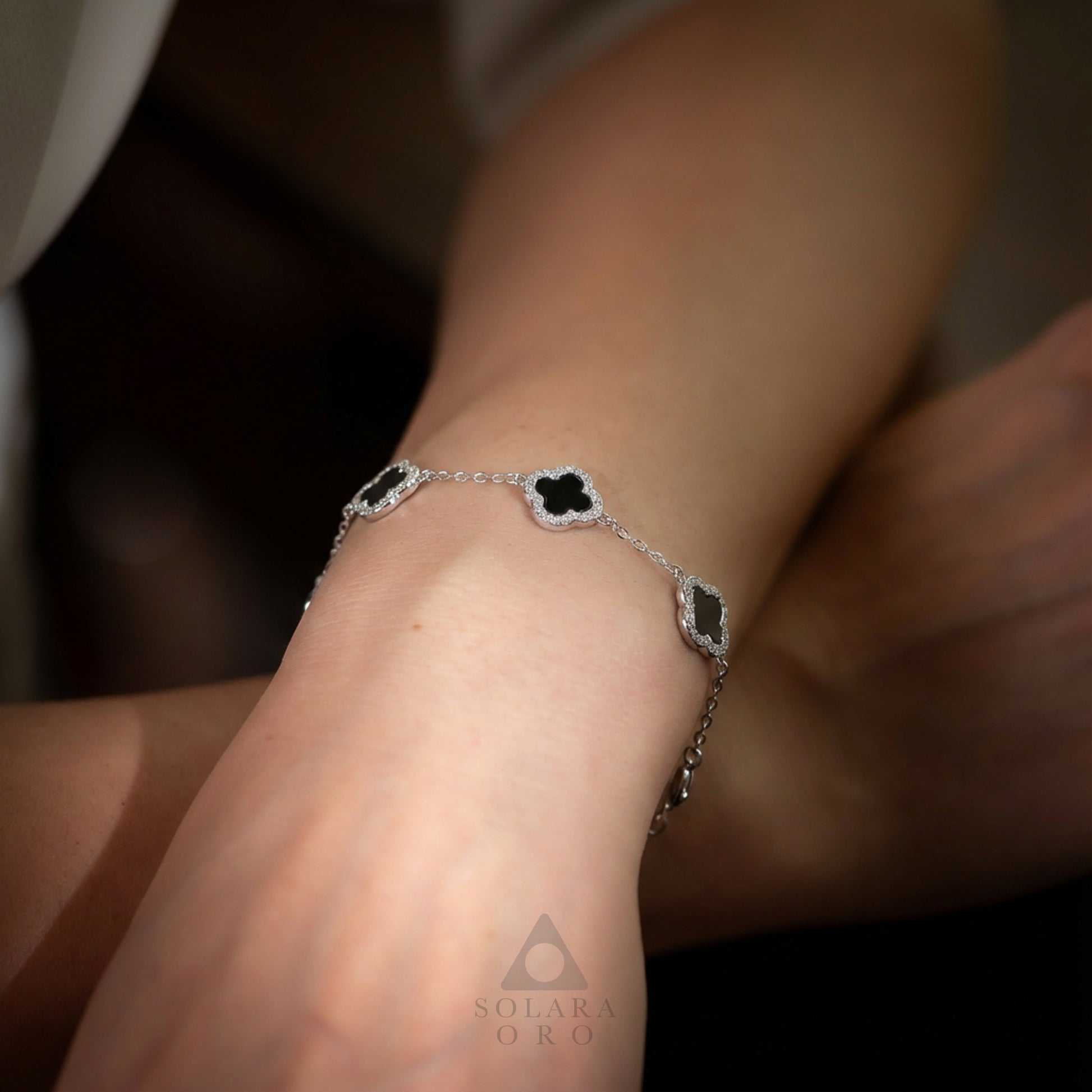 Silver bracelet with black stones on a wrist, brand 'Solara Oro' visible.