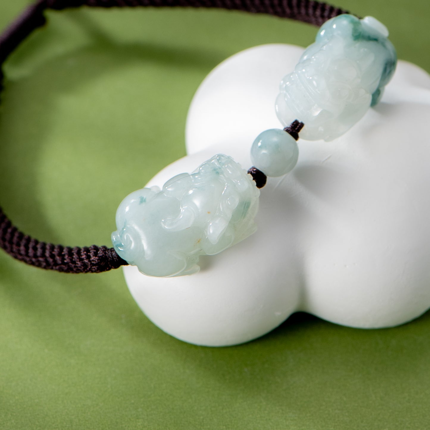 Green jade pendant on a white stand with a green background
