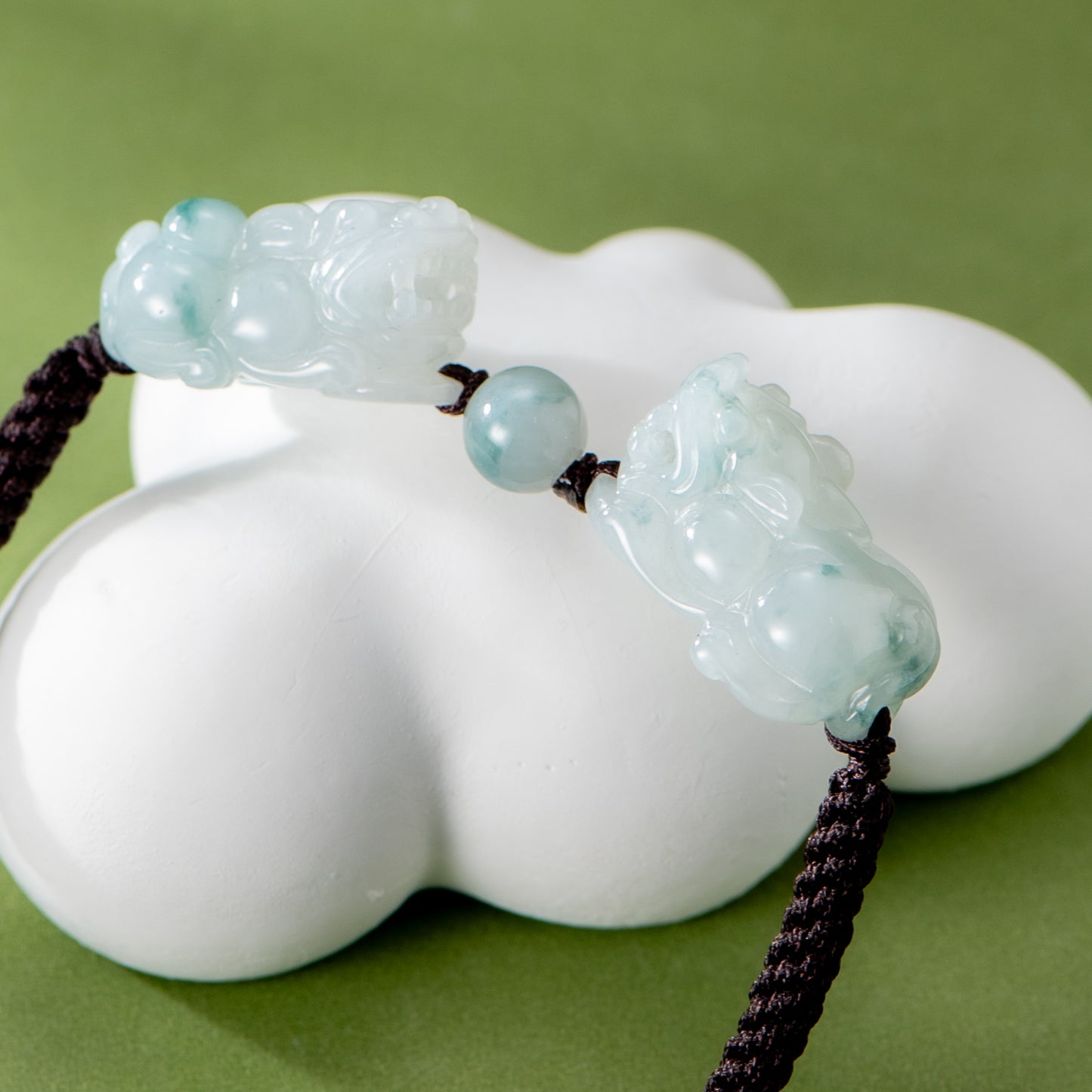 Green jade pendant on a white cloud-shaped object with a green background