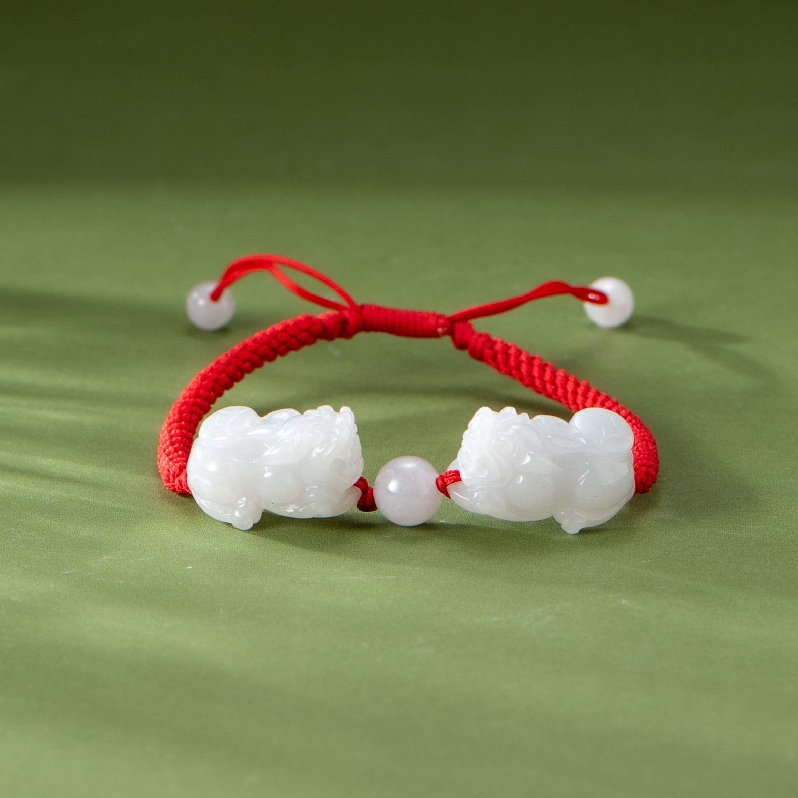 Bracelet with white beads and red cord on a green background