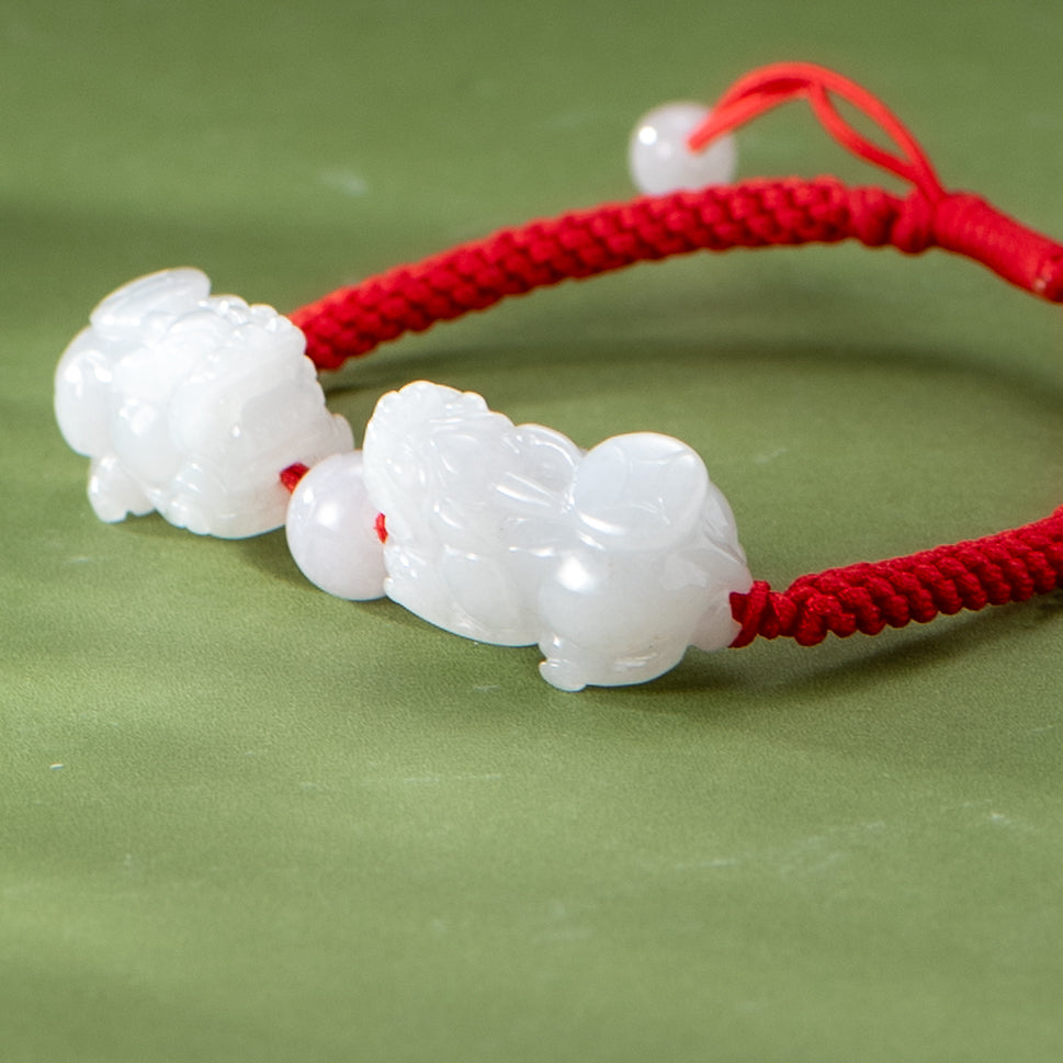 White jade beads on a red string bracelet on a green background