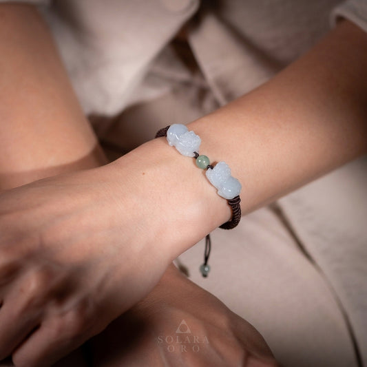 Close-up of a wrist wearing a bracelet with light blue beads, brand 'Solara Oro' visible.