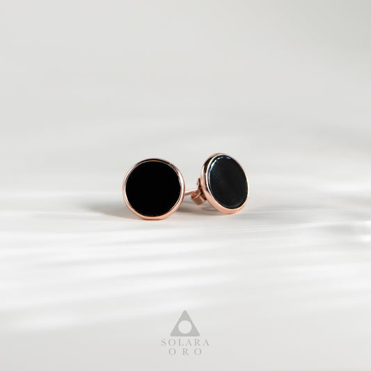 Pair of black round earrings with rose gold posts on a white background, branded 'Soleara Oro'.