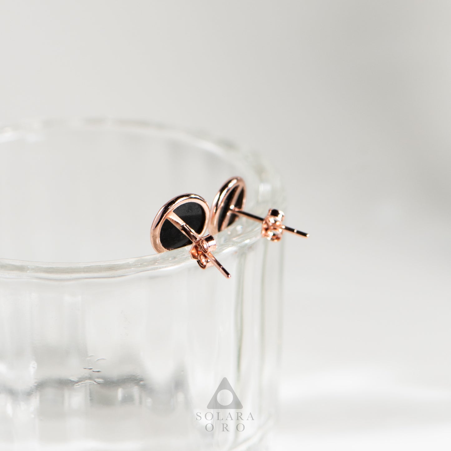Rose gold earrings with black heart design on a white background