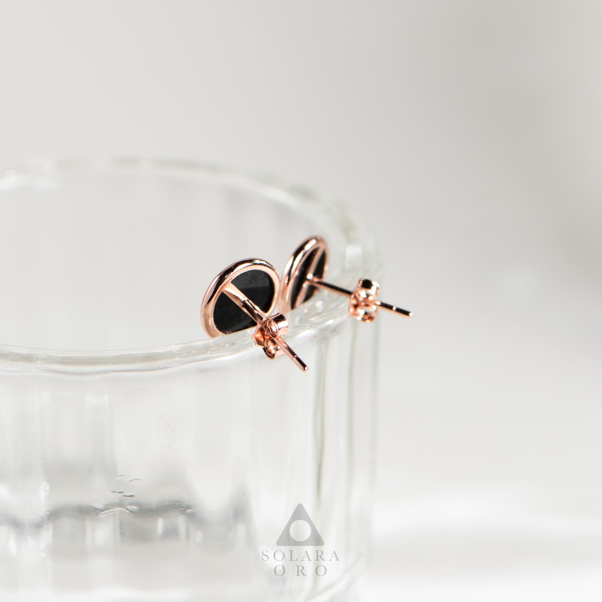 Rose gold earrings with black heart design on a white background