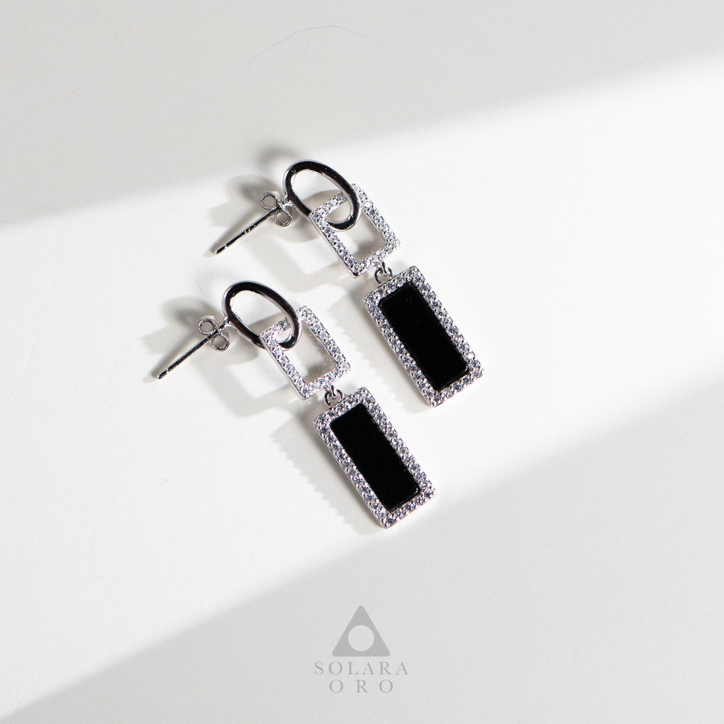 Pair of earrings with black rectangular stones and silver accents on a white background, branded 'Soleara Oro'.