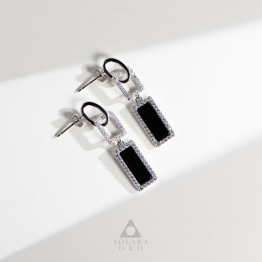 Pair of earrings with black rectangular stones and silver accents on a white background, branded 'Soleara Oro'.
