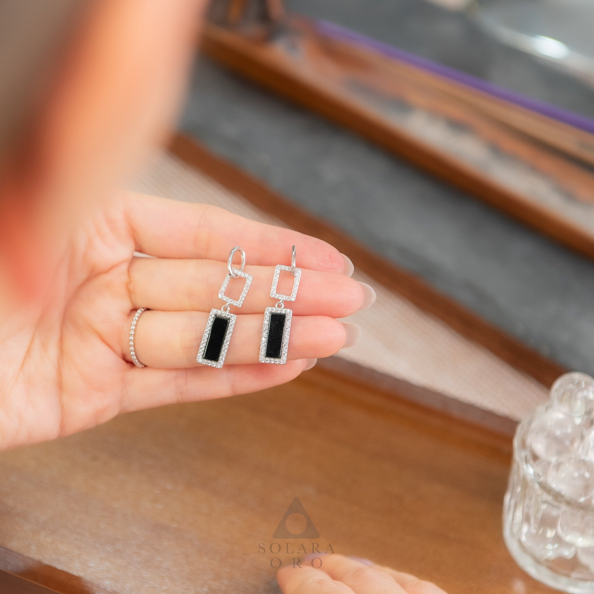 Hand holding a pair of earrings with a blurred background