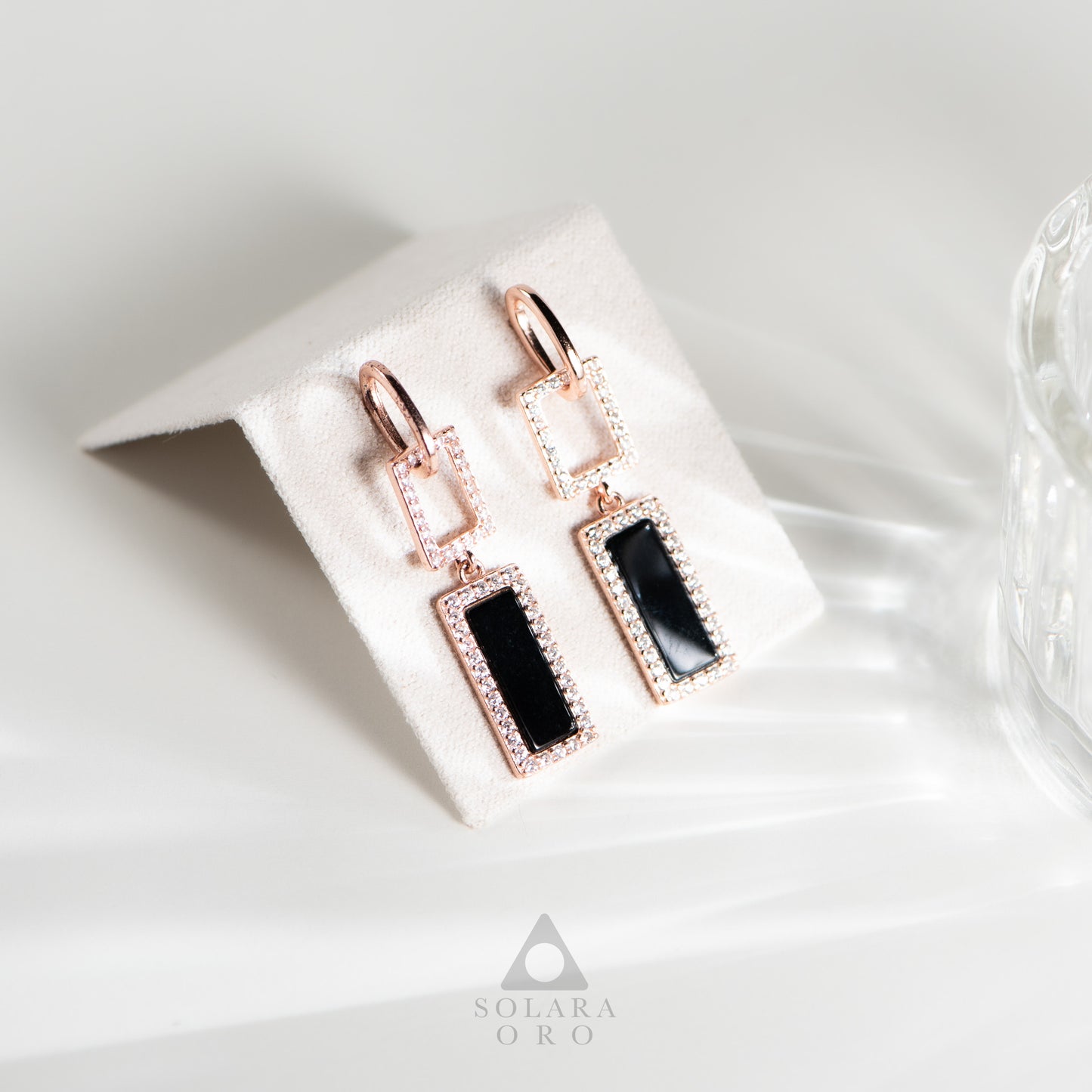 Rose gold earrings with black stones on a white card, branded 'Soleara Oro'.
