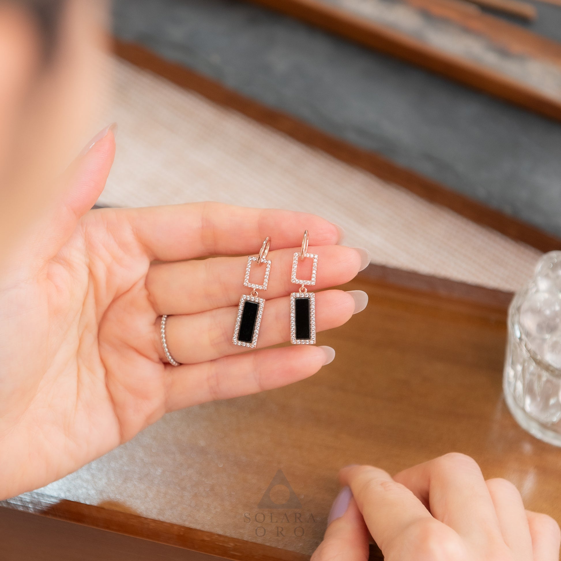 Hand holding a pair of earrings with a blurred background