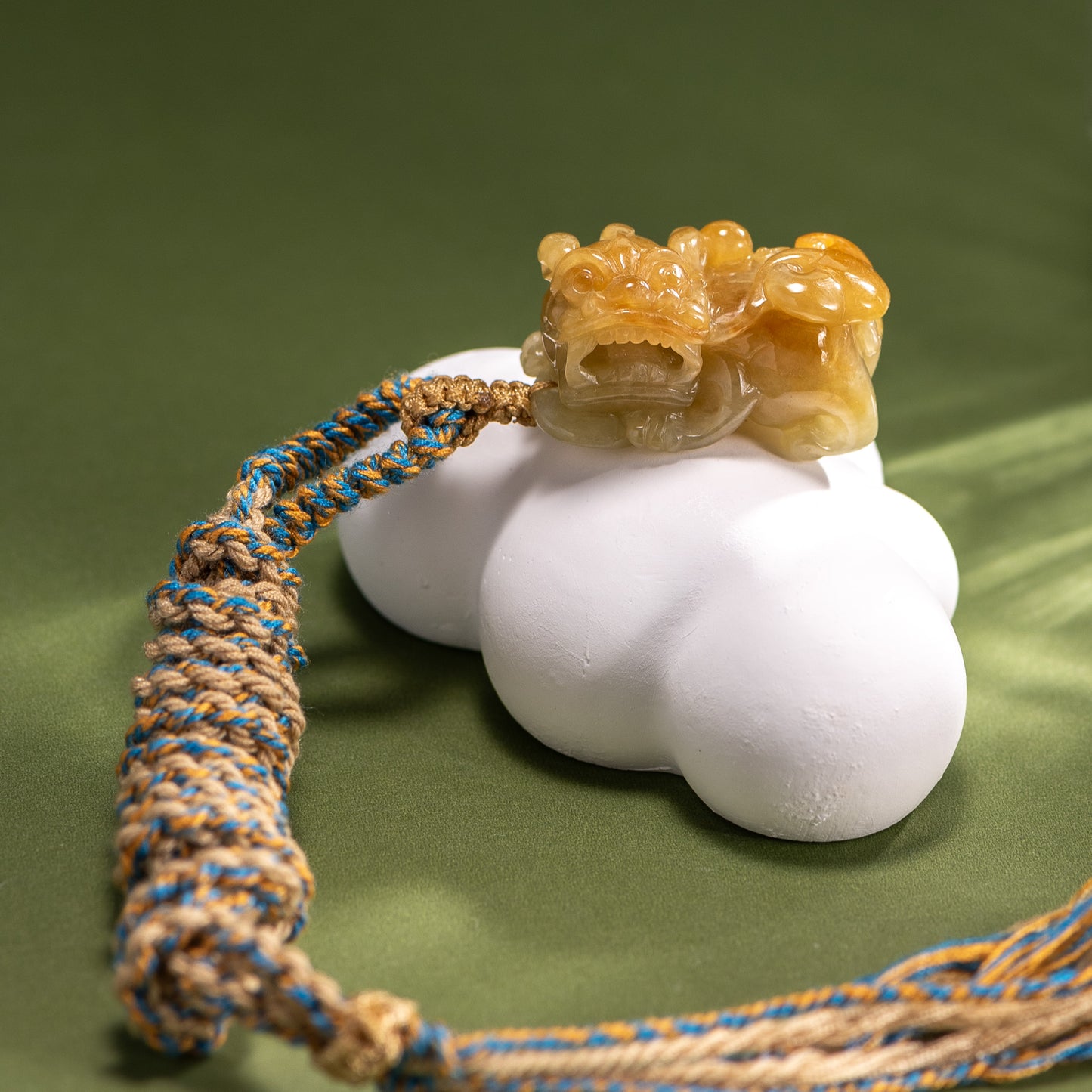 Decorative item with a carved dragon figure on a white base with a braided rope, against a green background.