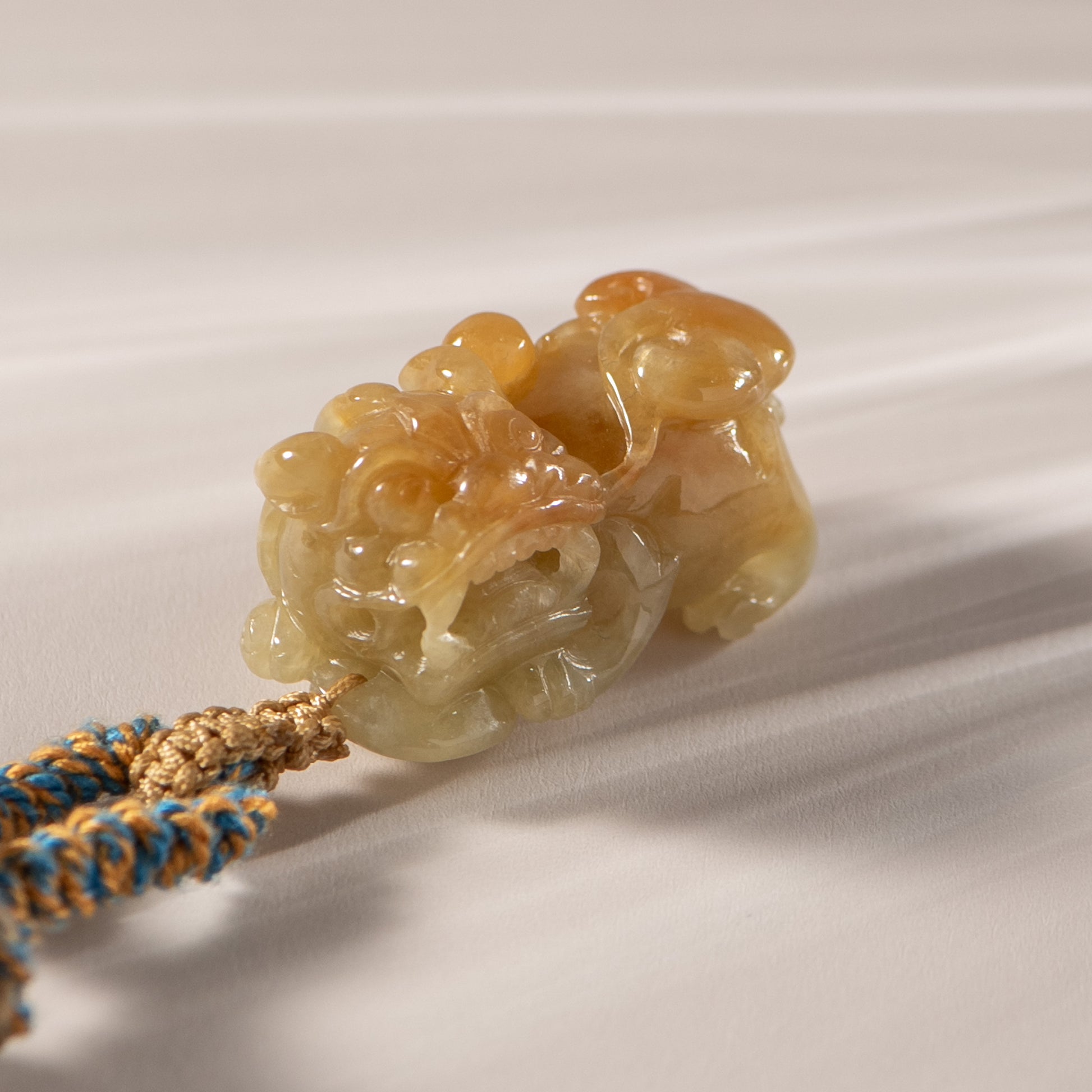 Carved stone pendant on a cord against a neutral background