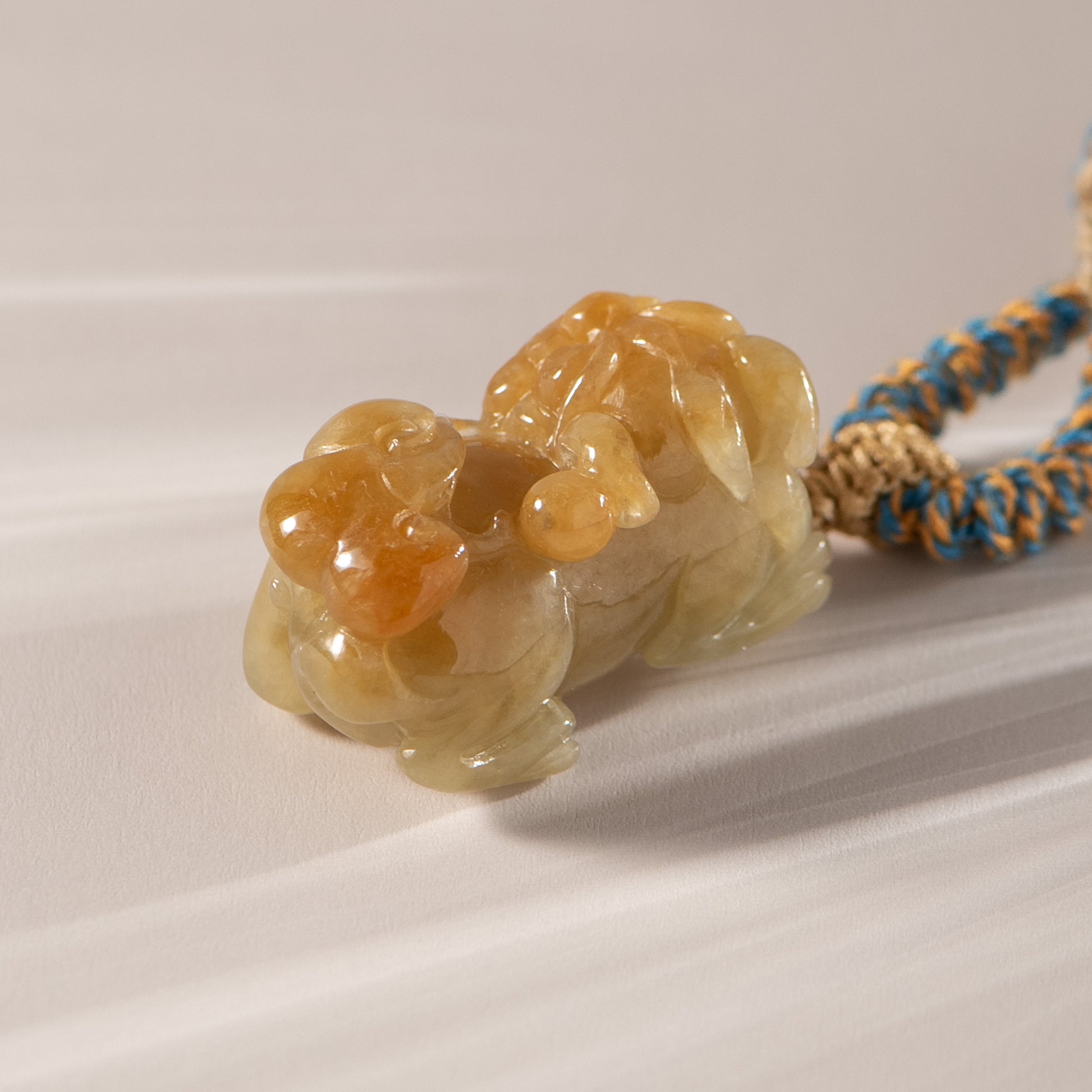 Carved stone lion pendant on a braided cord against a white background