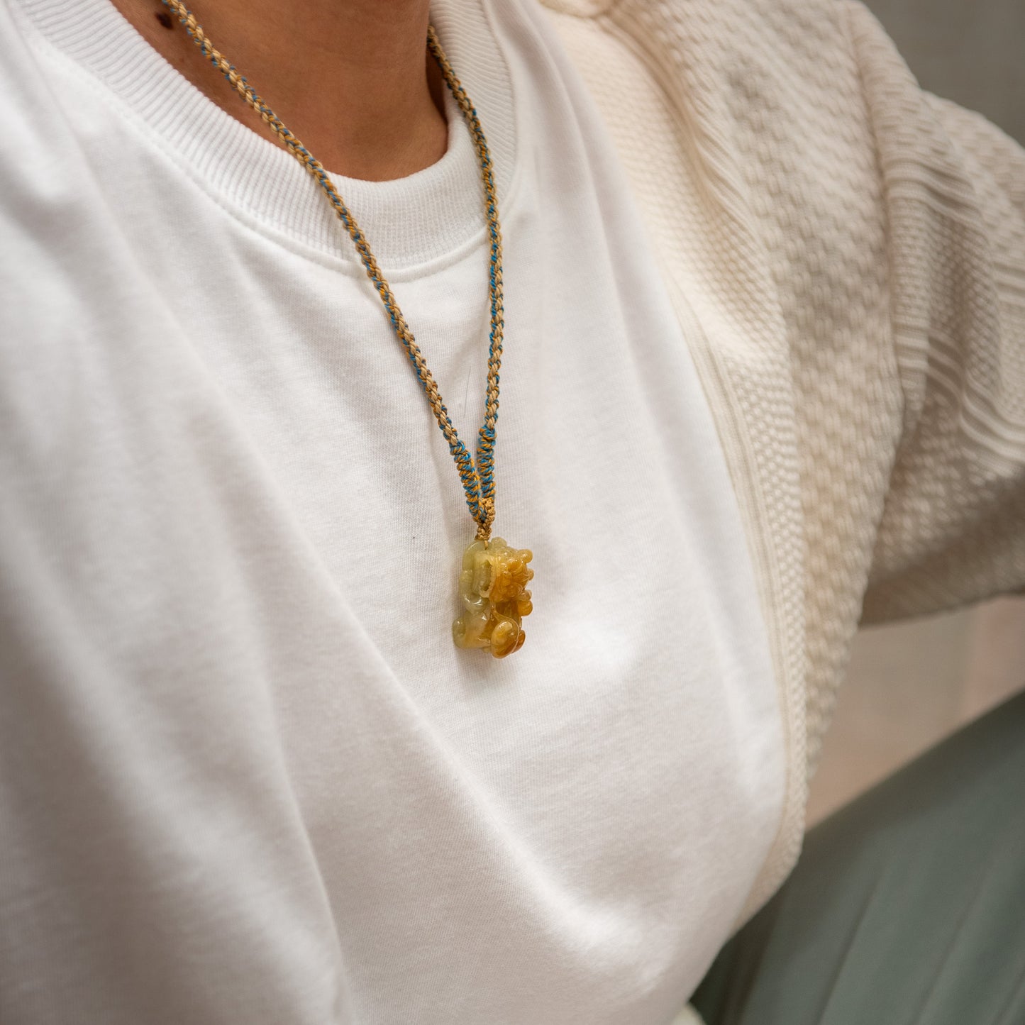 Close-up of a person wearing a necklace with a yellow pendant.