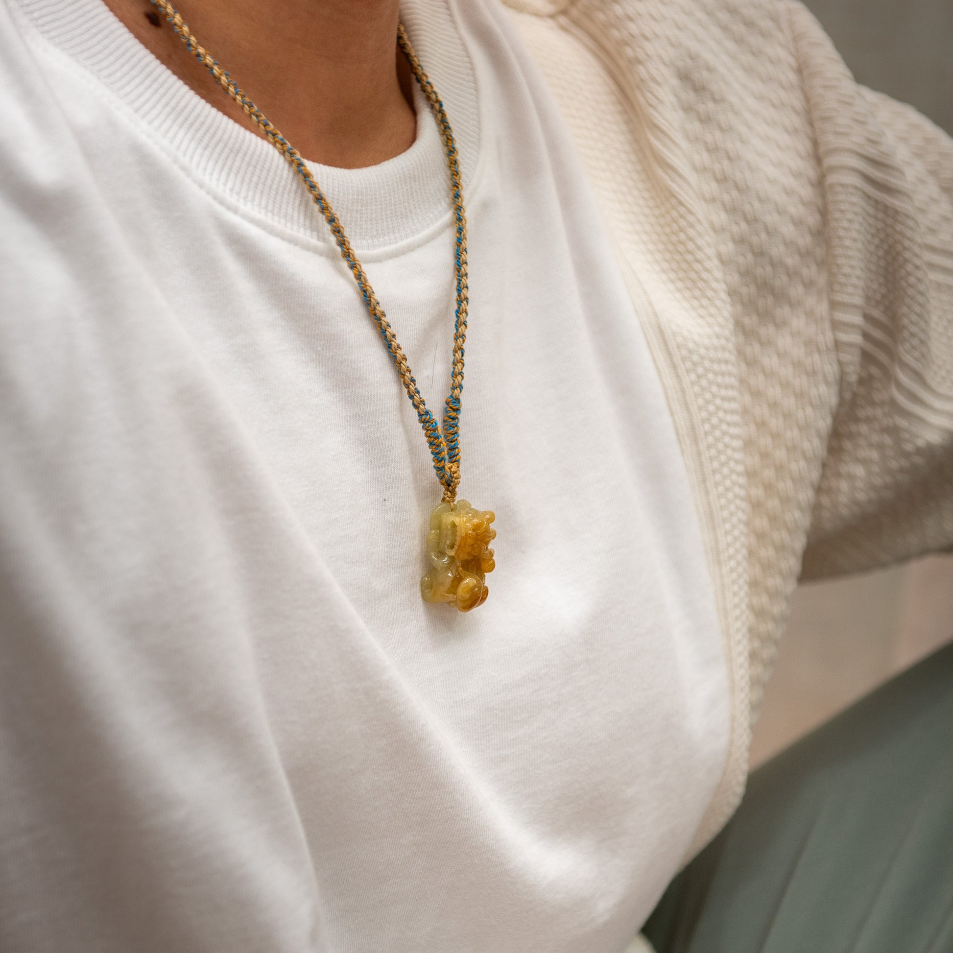 Close-up of a person wearing a necklace with a yellow pendant.