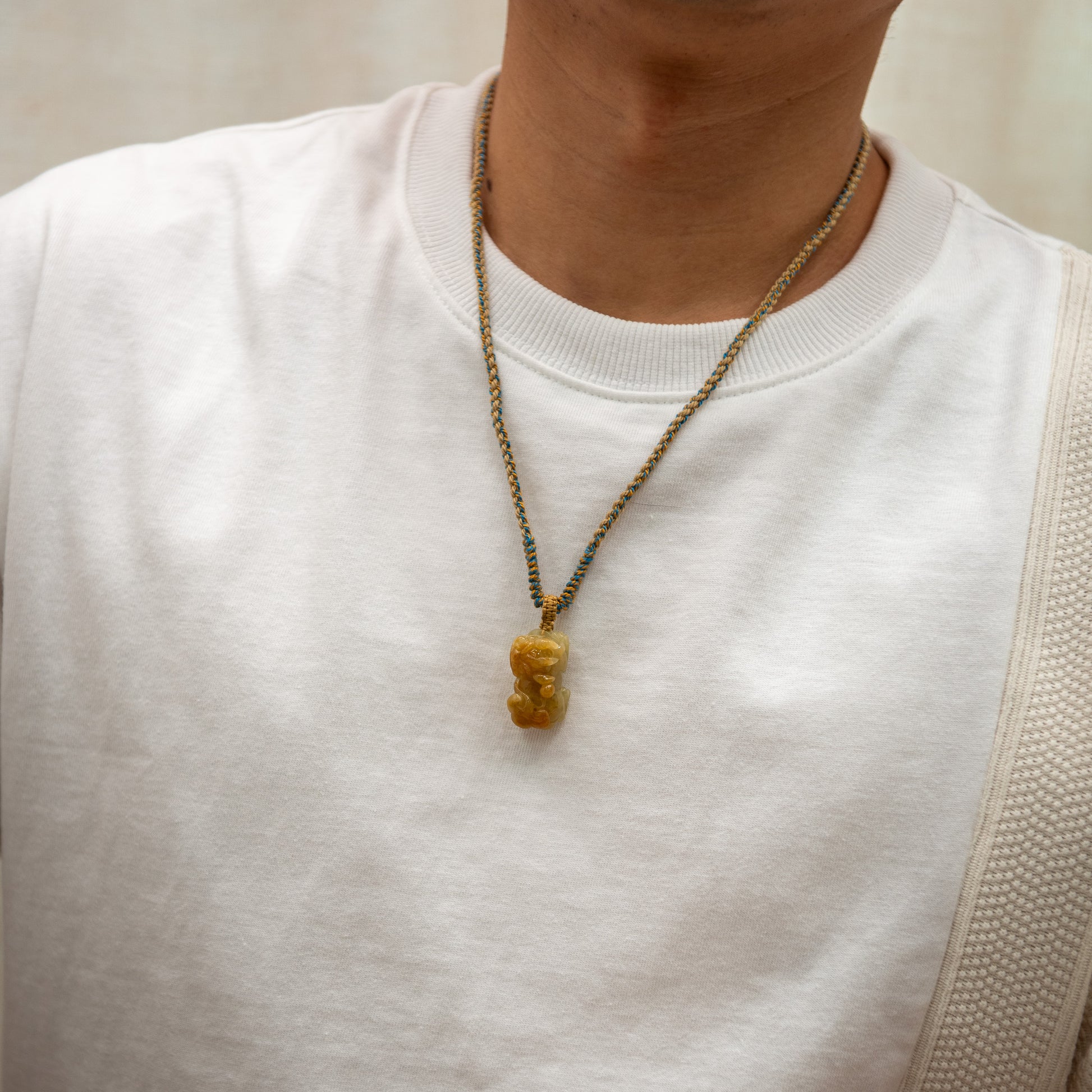 Person wearing a necklace with a unique pendant on a plain background