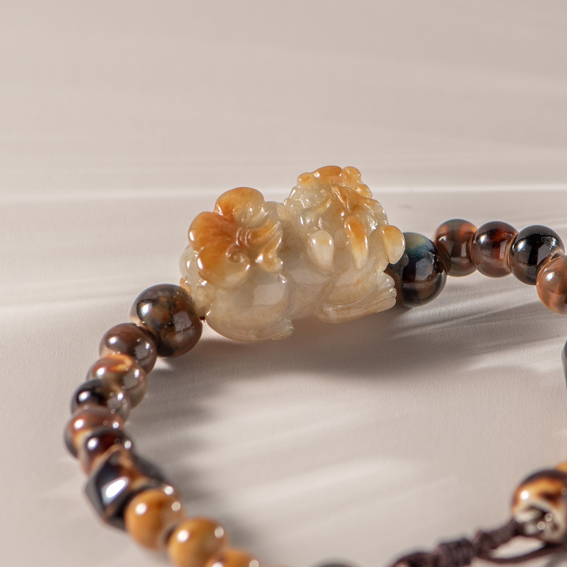 Bracelet with brown and black beads and a carved stone lion charm on a light background