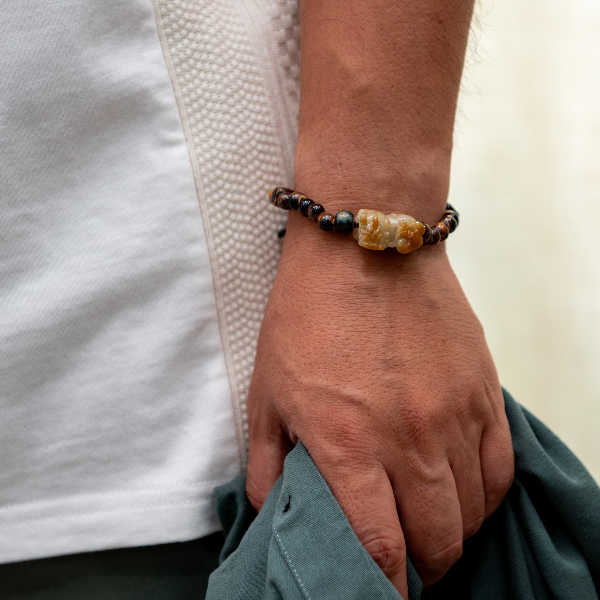 Hand wearing a beaded bracelet with a neutral background