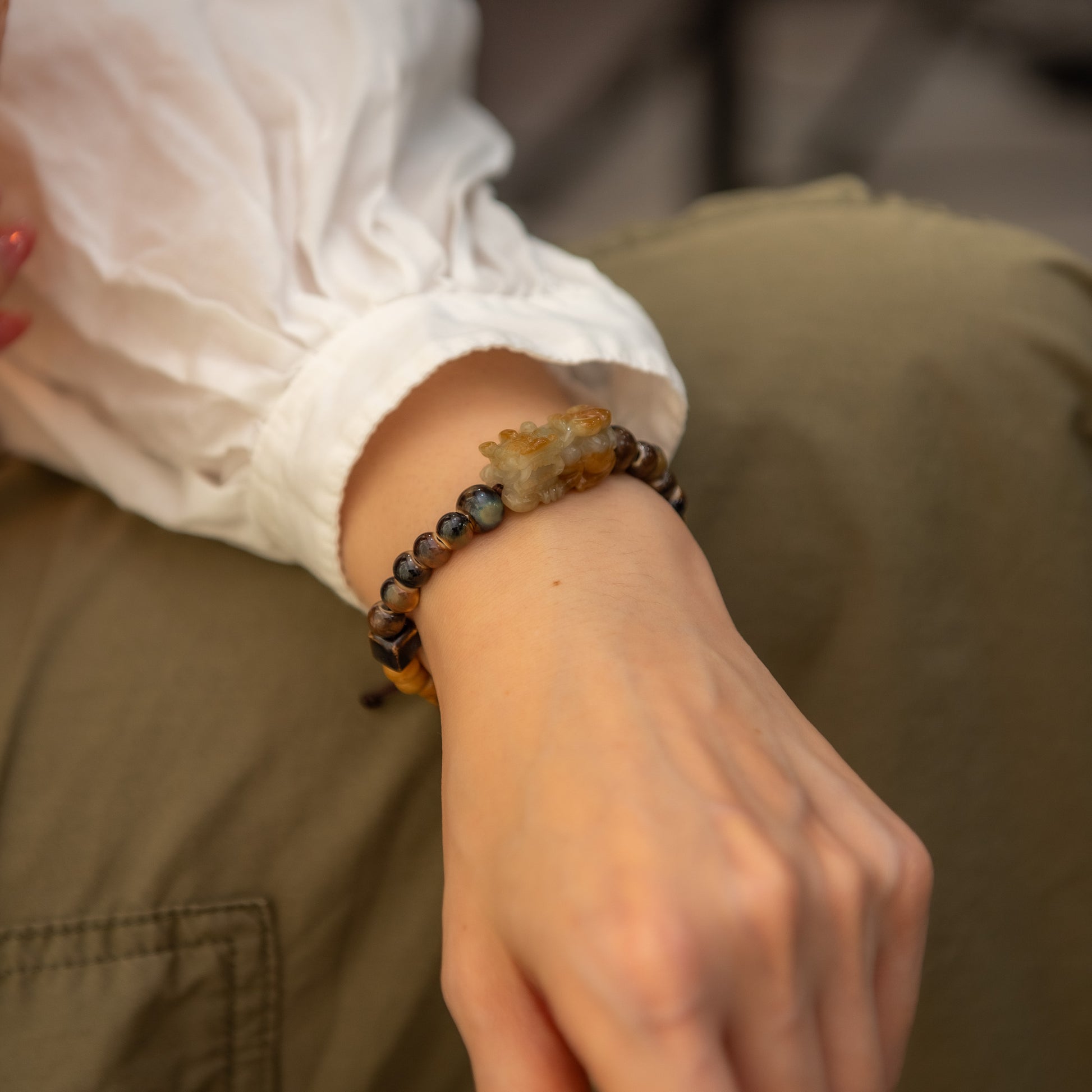 Close-up of a wrist wearing a beaded bracelet with a blurred background