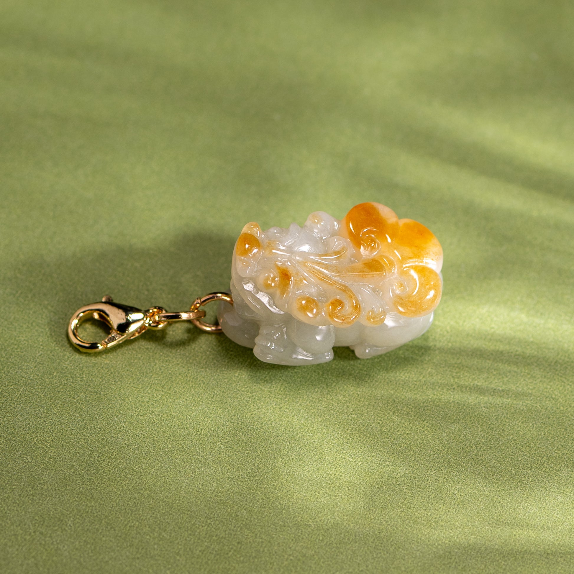 Decorative charm with gold clasp on a green fabric background