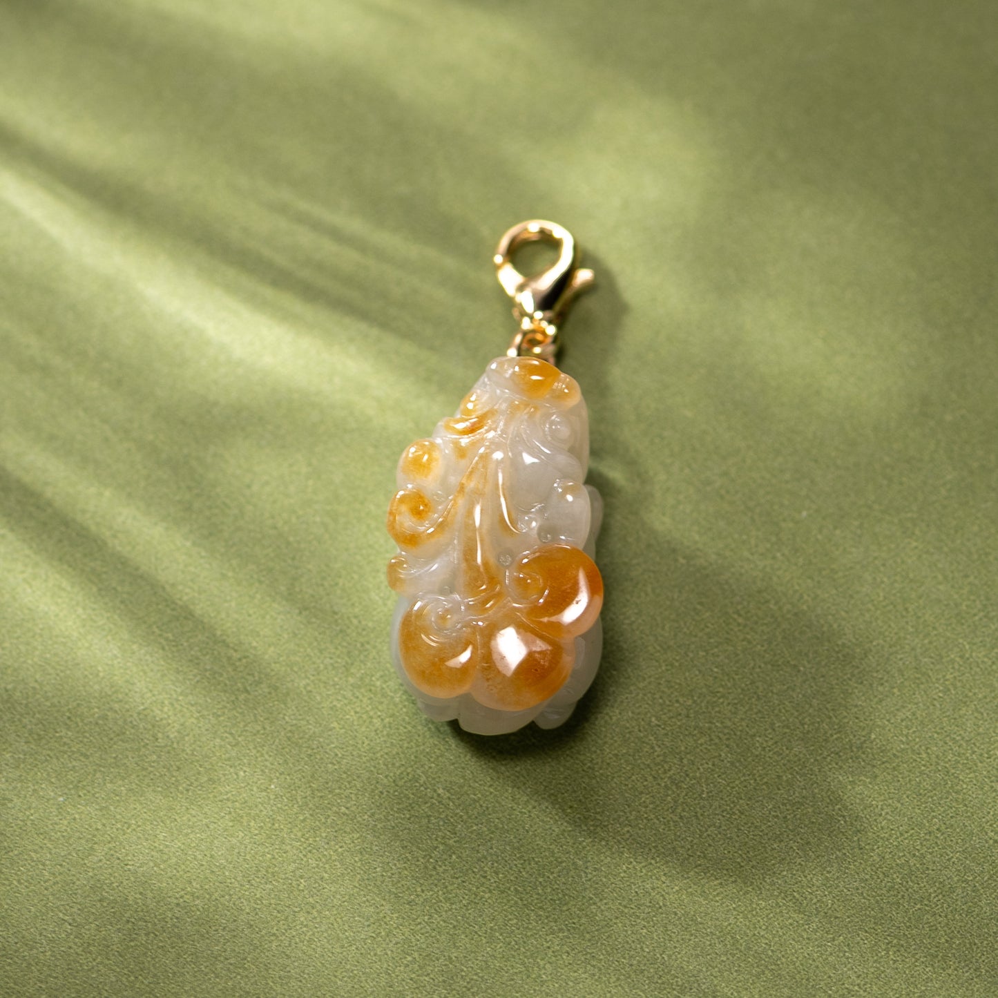 Decorative pendant with gold accent on a green fabric background