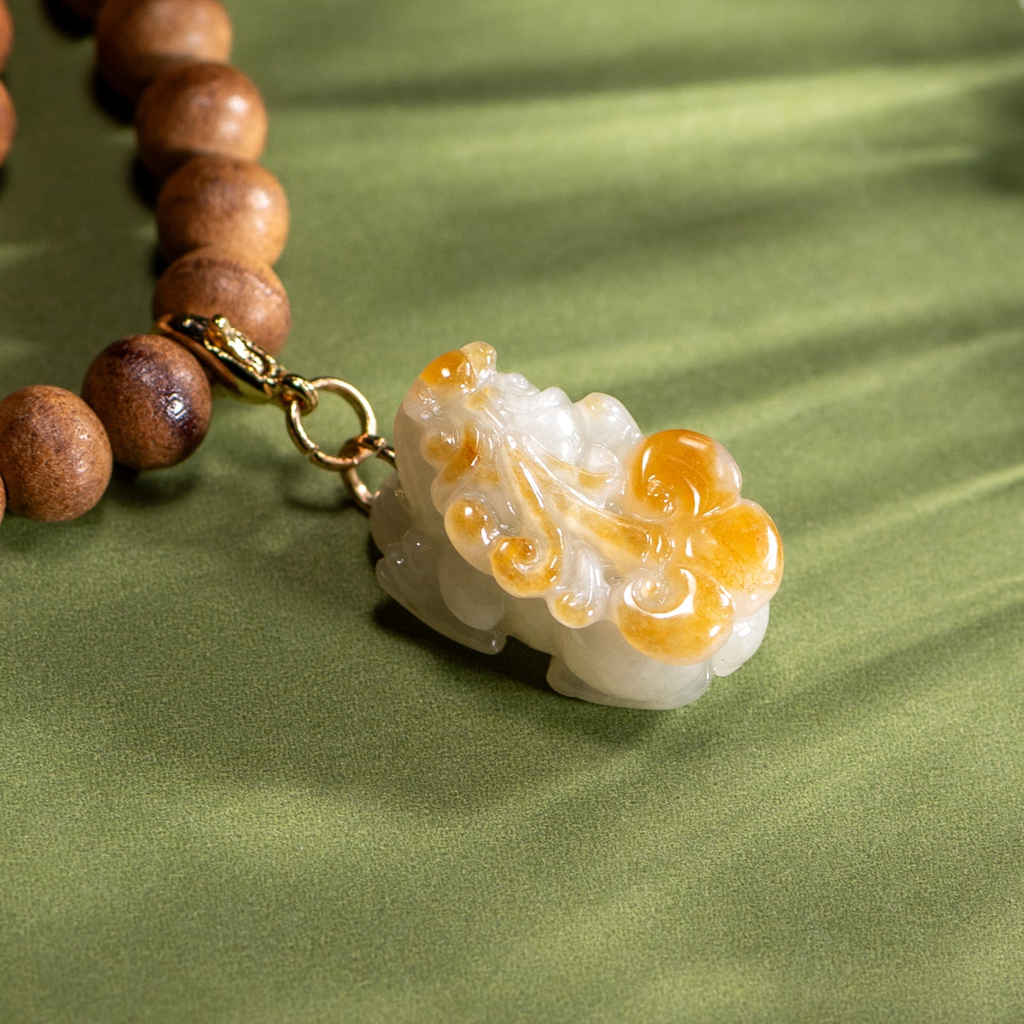 Necklace with wooden beads and a decorative pendant on a green fabric background