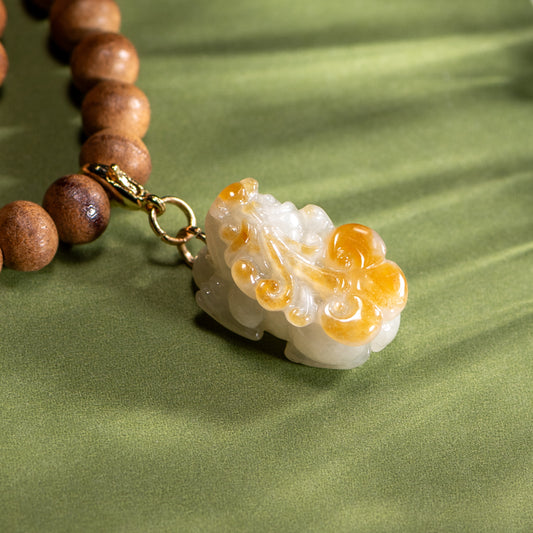 Necklace with wooden beads and a decorative pendant on a green fabric background
