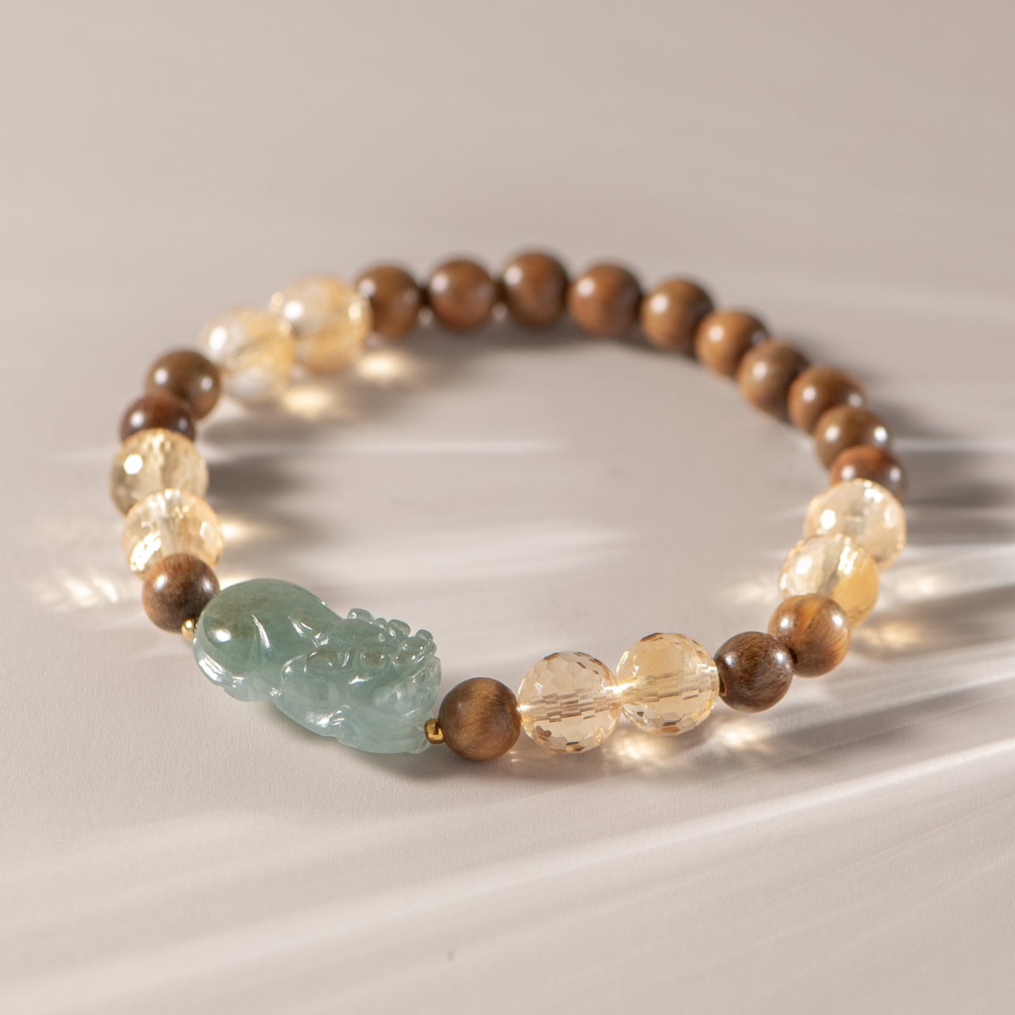 Beaded bracelet with a green stone and wooden beads on a reflective surface
