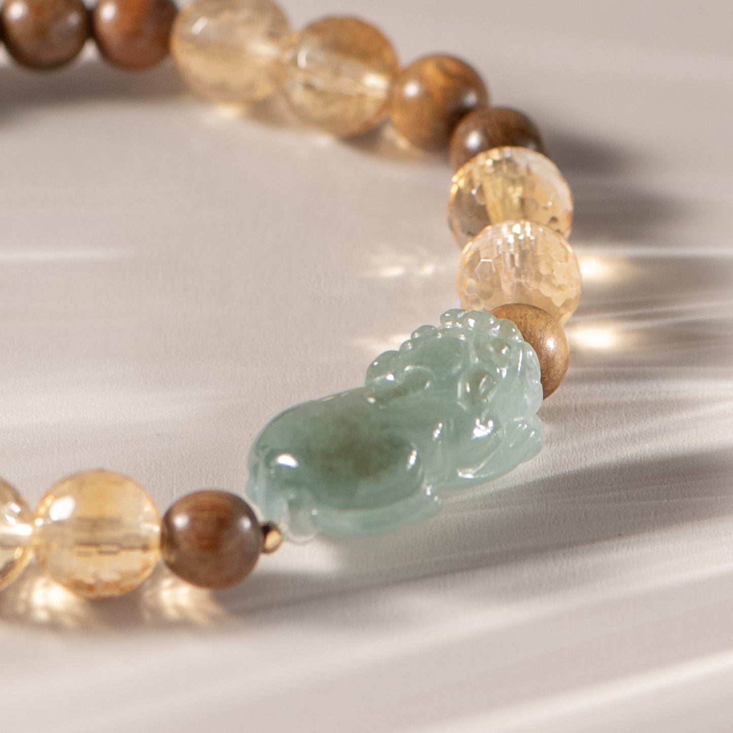 Beaded bracelet with a jade charm on a reflective surface