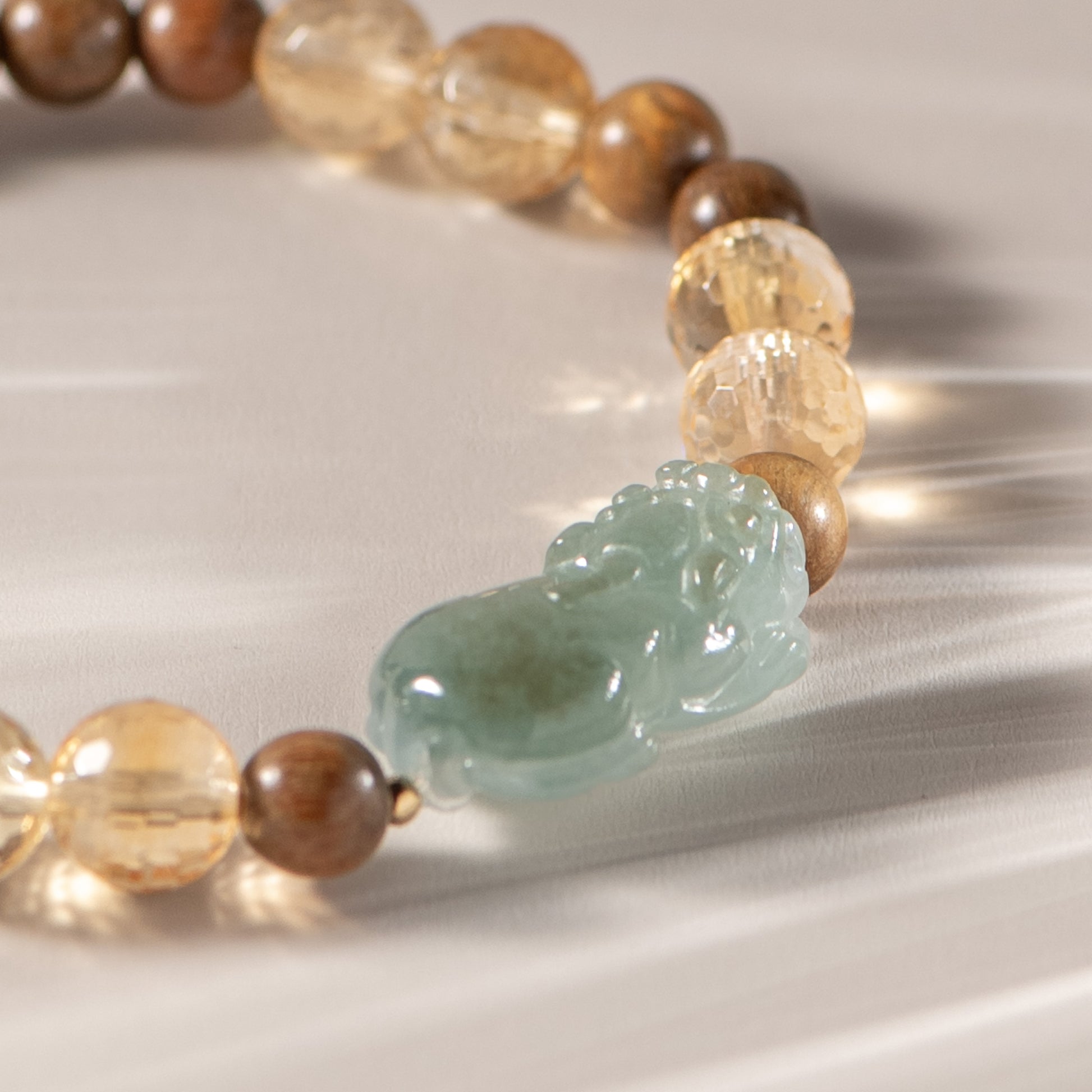 Beaded bracelet with a jade charm on a reflective surface
