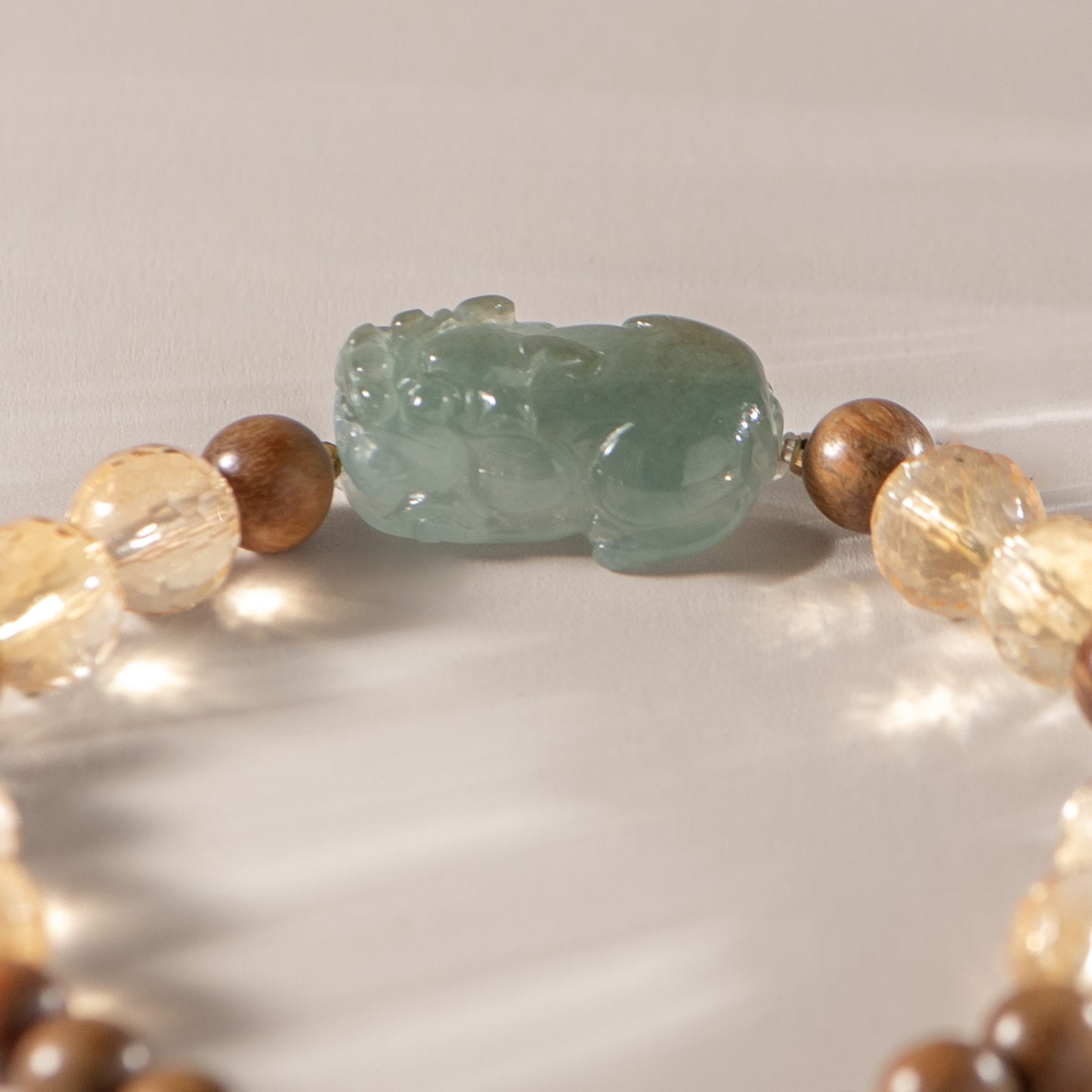 Necklace with a green jade pendant and multicolored beads on a neutral background
