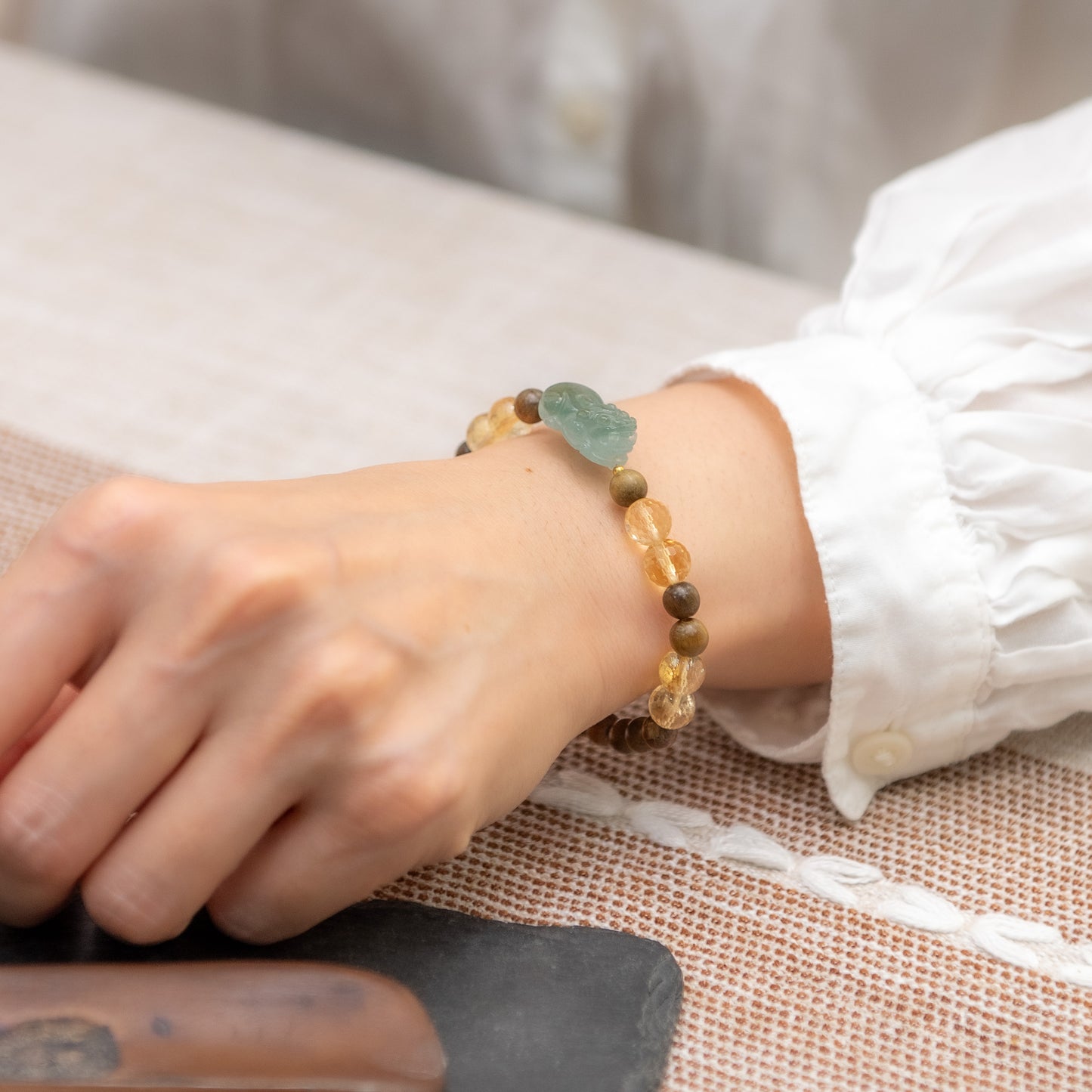 Close-up of a wrist wearing a beaded bracelet on a textured surface