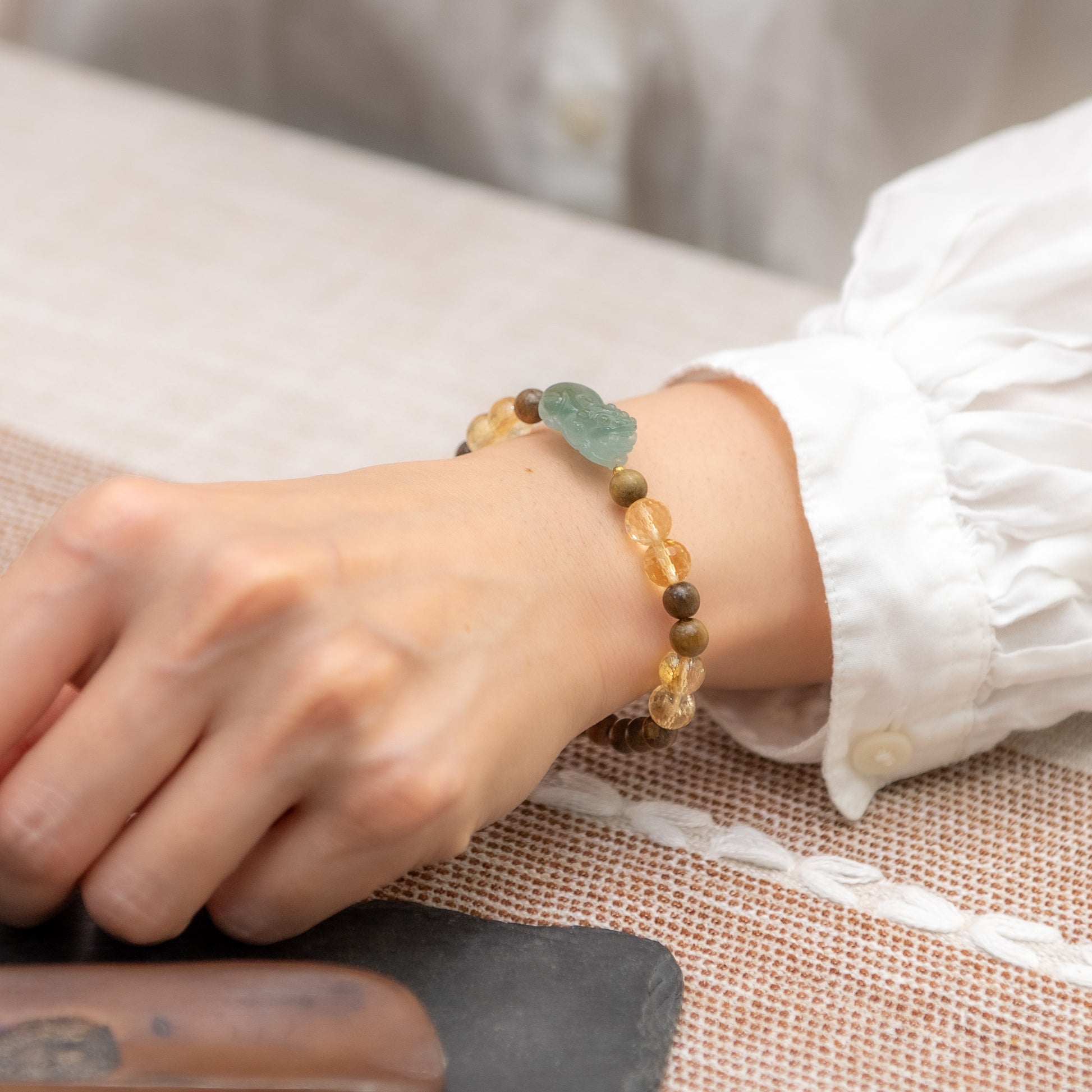 Close-up of a wrist wearing a beaded bracelet on a textured surface