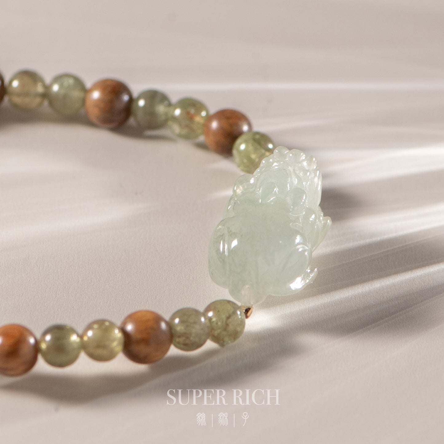 Beaded bracelet with a large green stone on a neutral background, featuring the brand 'Super Rich'.