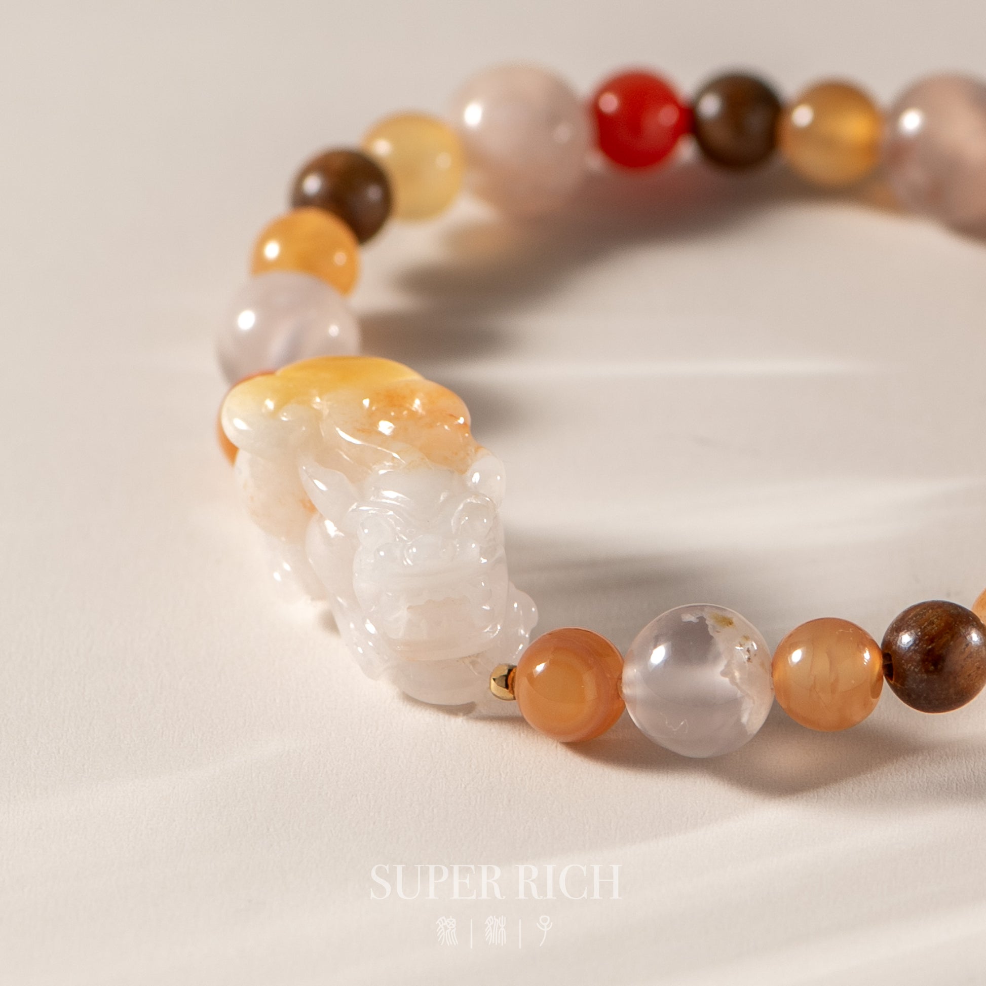Beaded bracelet with a large carved stone on a light background, featuring the brand 'Super Rich'.