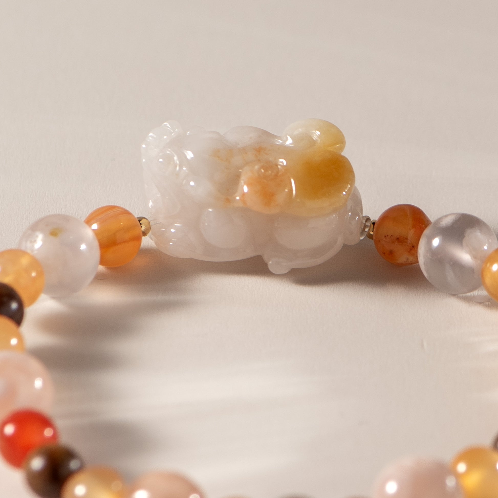 Close-up of a beaded bracelet with a carved stone panda bead on a white background
