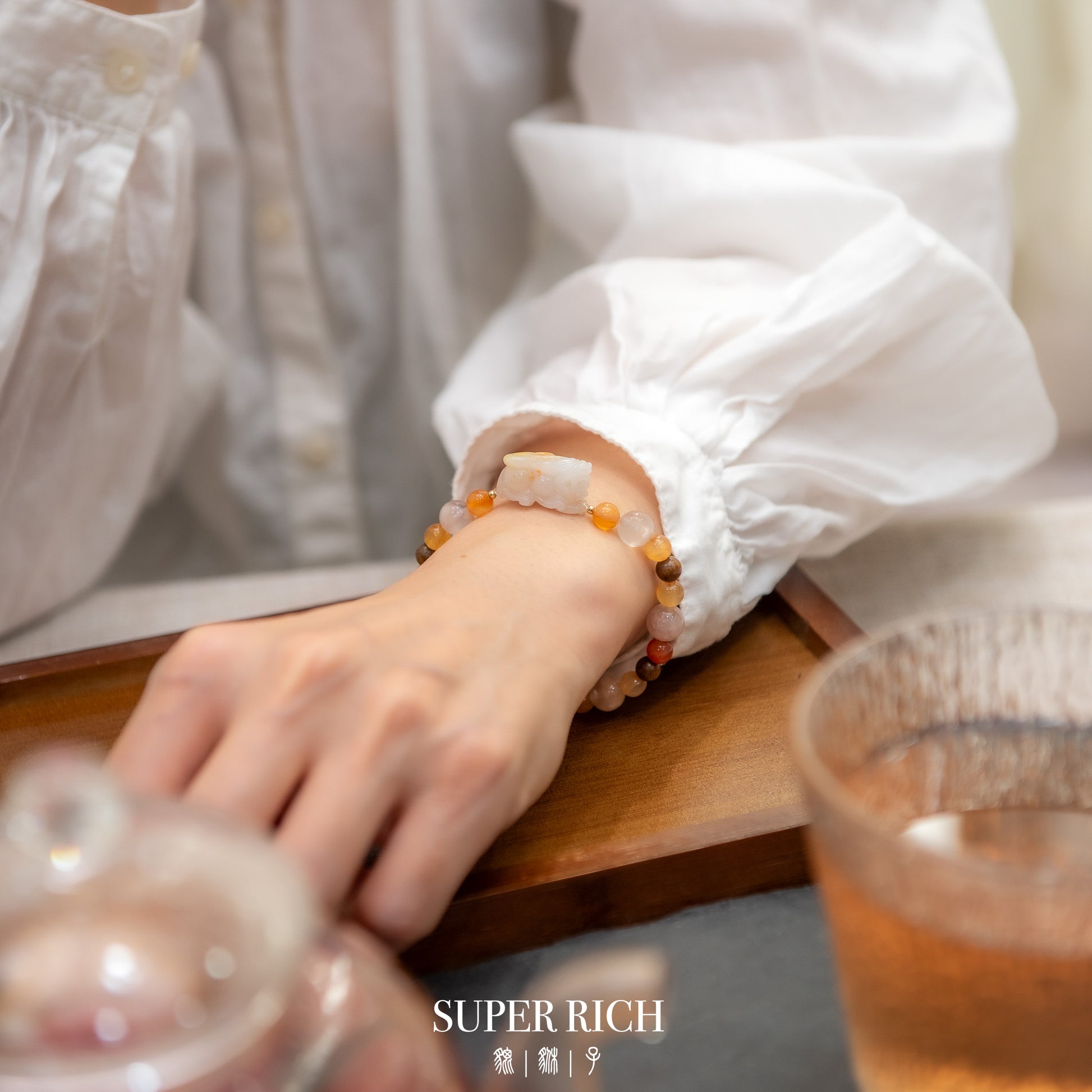 Person wearing a bracelet with a glass of tea in the foreground